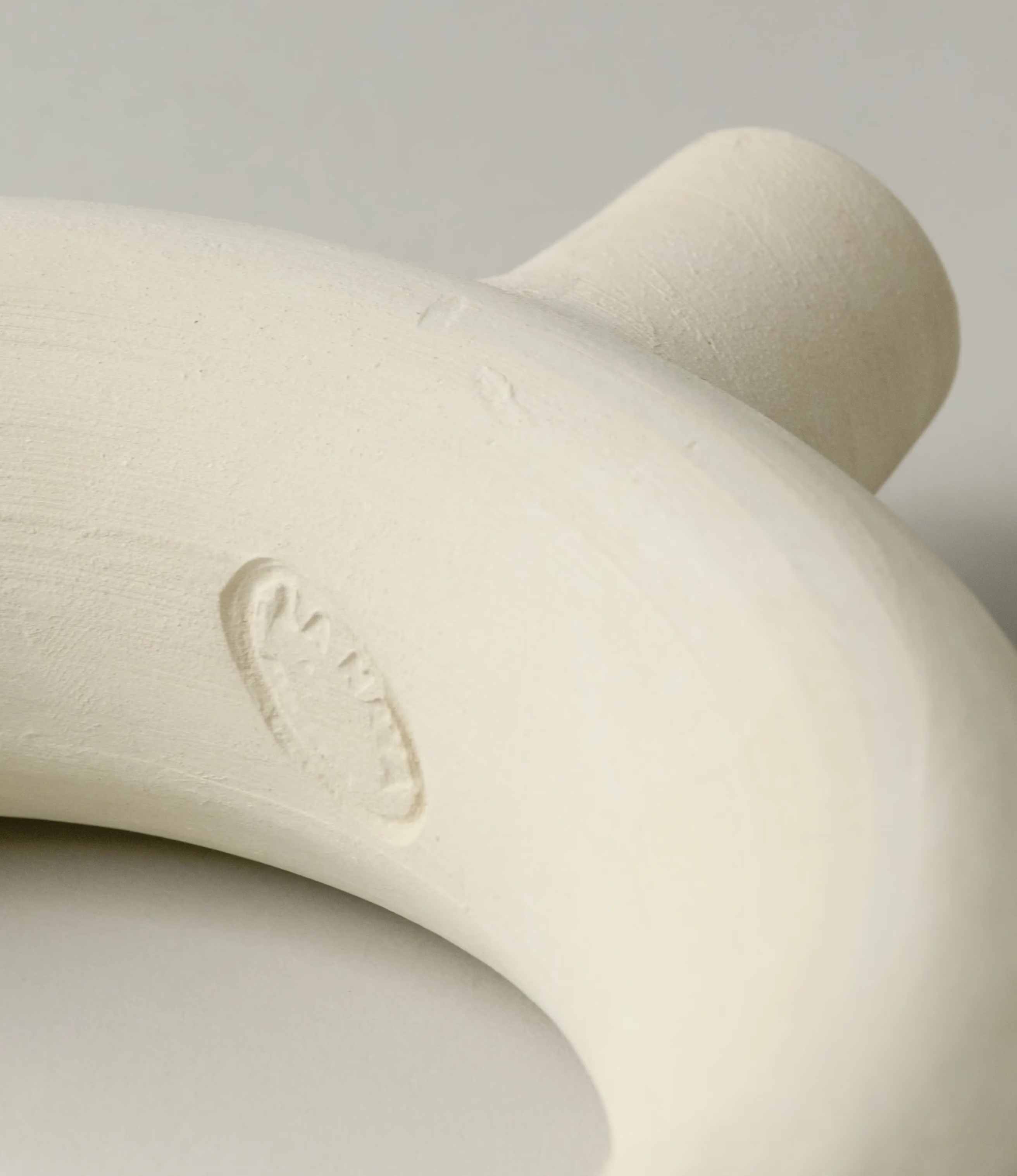 Arc Candle Holder from Alfareria La Nava comes in the color raw white. It has a matt, raw finishing. The picture shows the embossed logo of Alfareria La Nava at the bottom of the product.