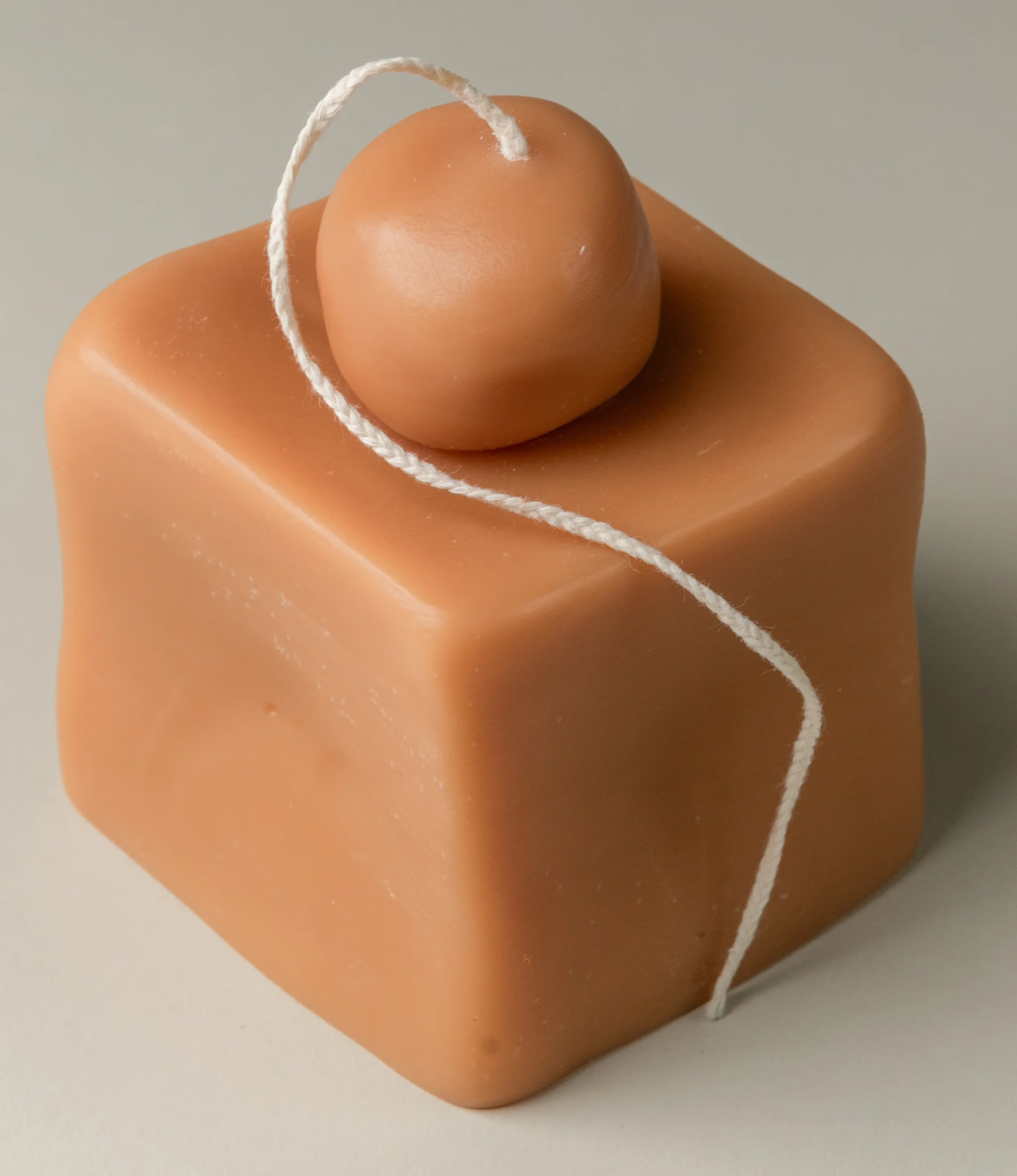 Fonz from Ann Vincent is a sculptural candle. The silhouette of the product looks like a rectangle with a smaller rounded shape on top. The candle wick is quite long and has a braided texture.
