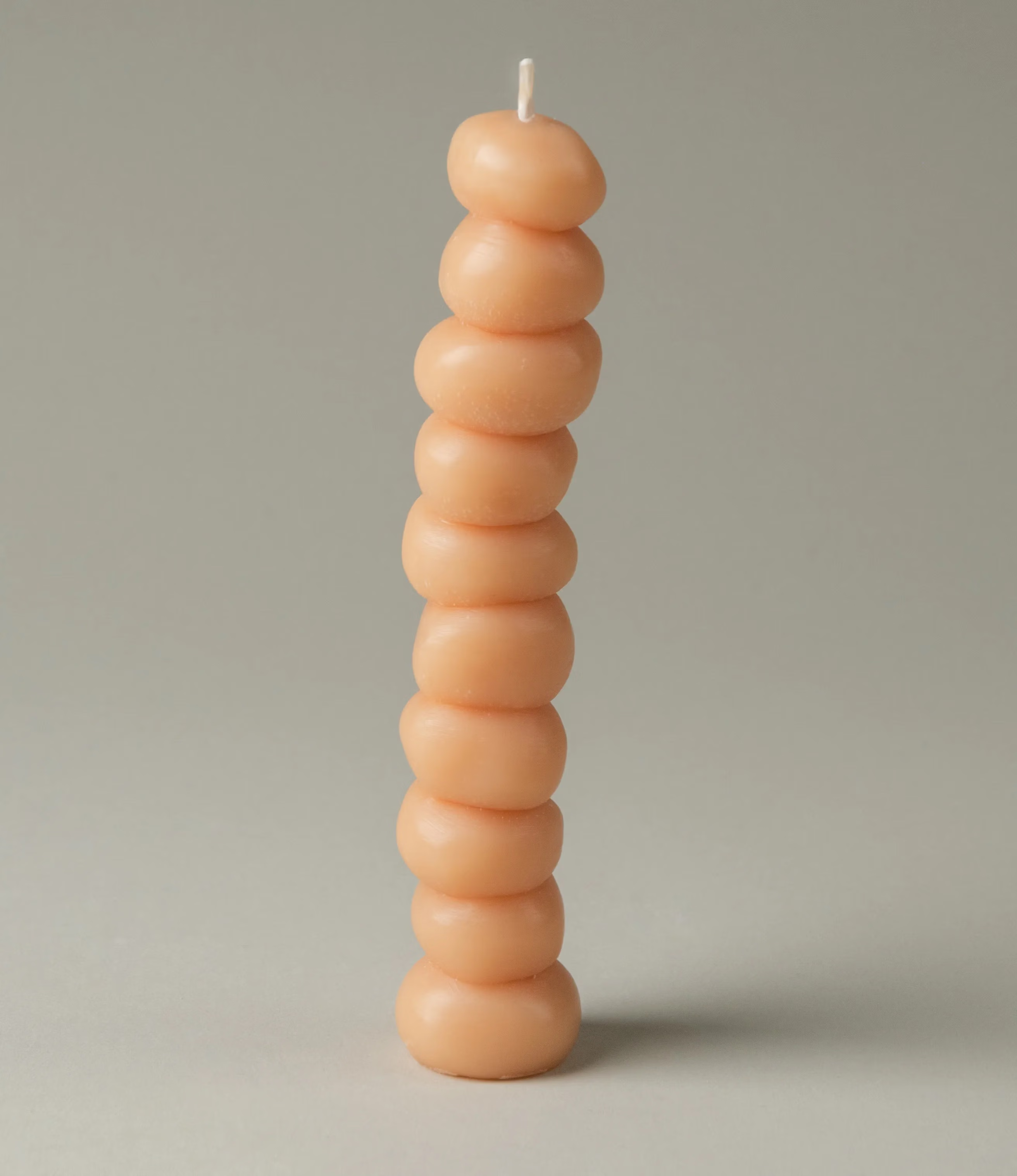 Grape Candle from Ann Vincent has the shape of grapes stacked on top of each other. It has a light nude color.