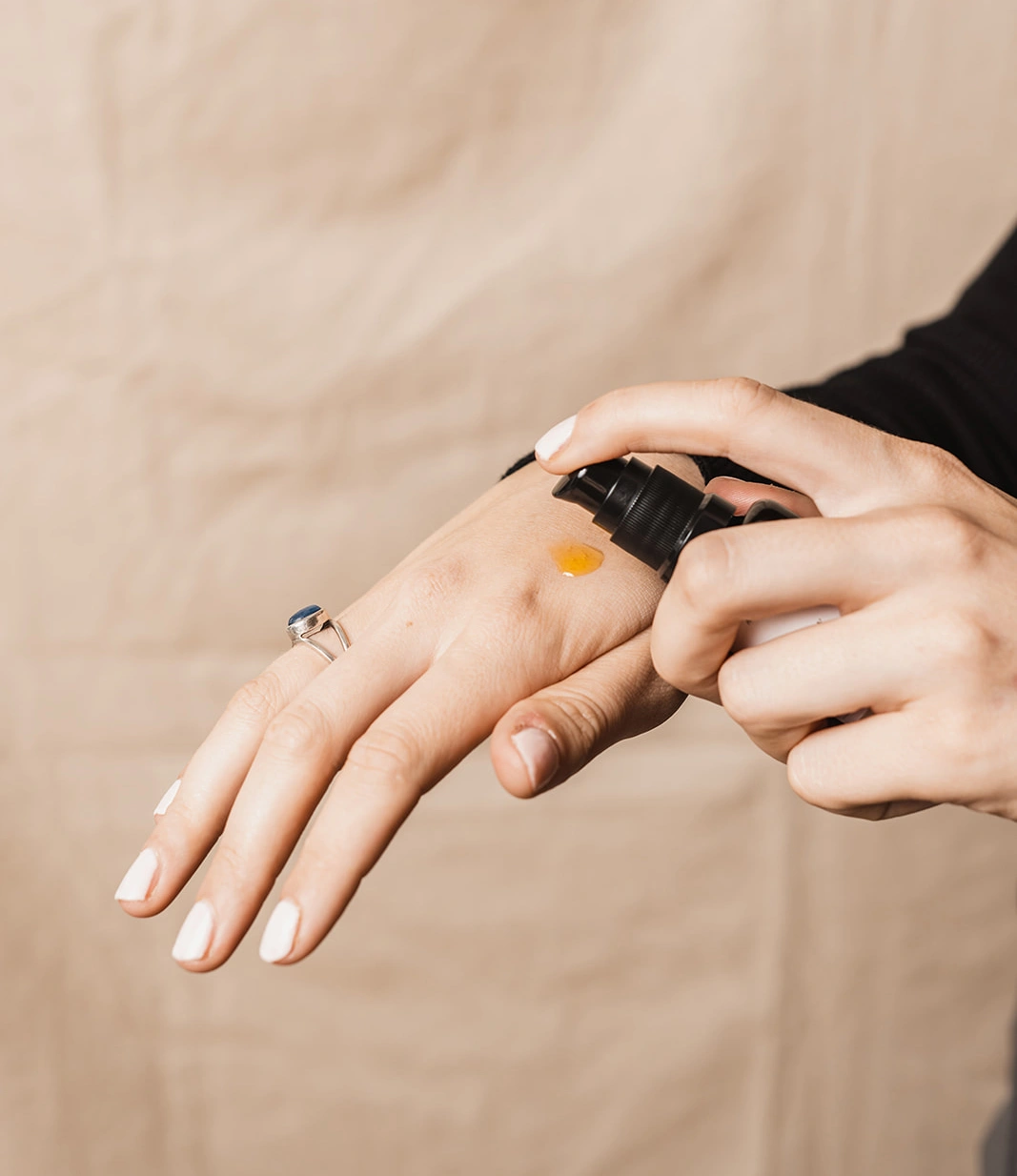 Natural Face Oil in use. The person is squeezes a small amount on her hand.