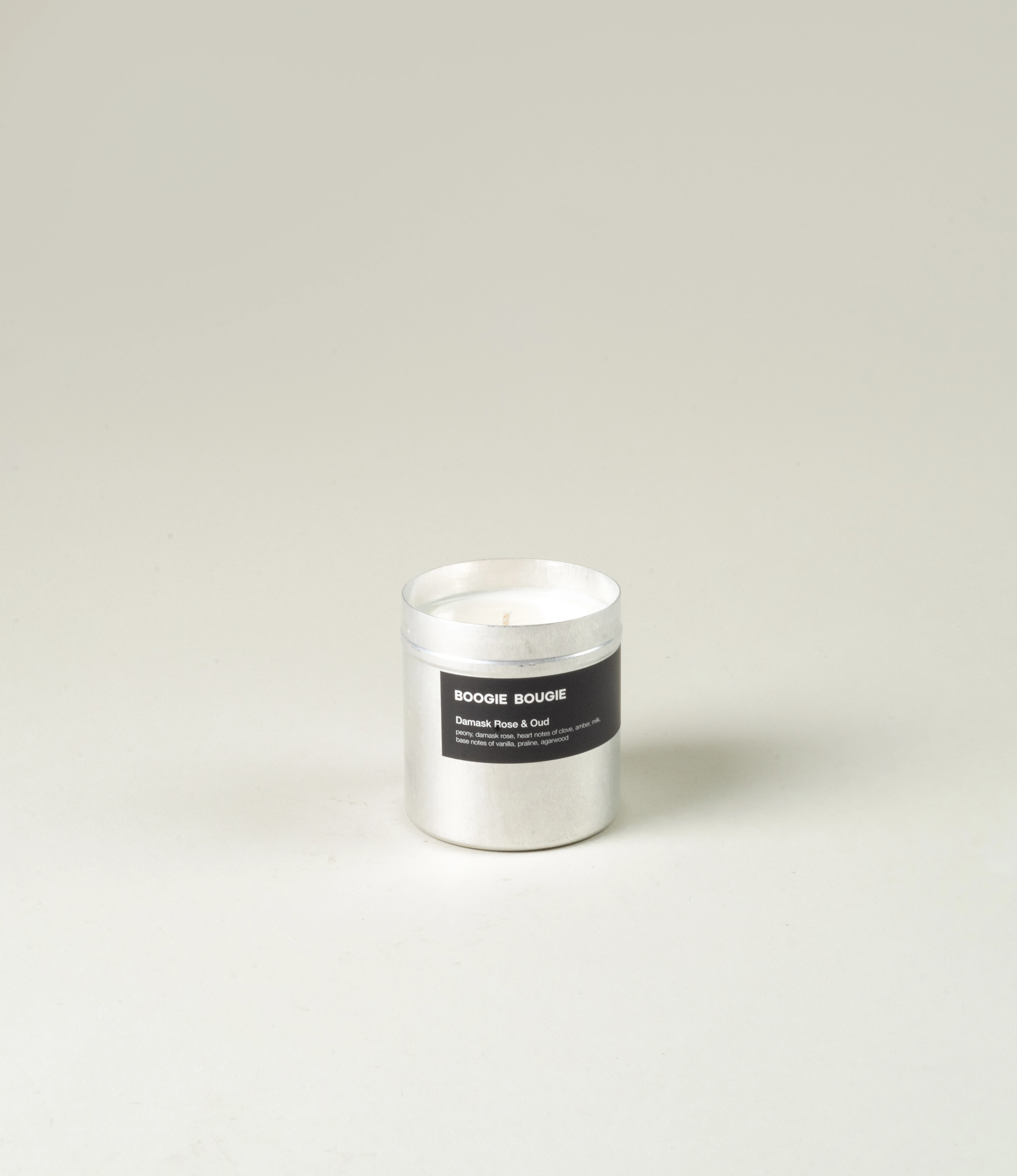 Boogie Bougie Damask Rose & Oud candle presented in its minimalist aluminum container. The sleek black label highlights the scent's luxurious ingredients, adding a touch of sophistication. The product is elegantly displayed against a soft neutral backdrop for a clean and refined look.
