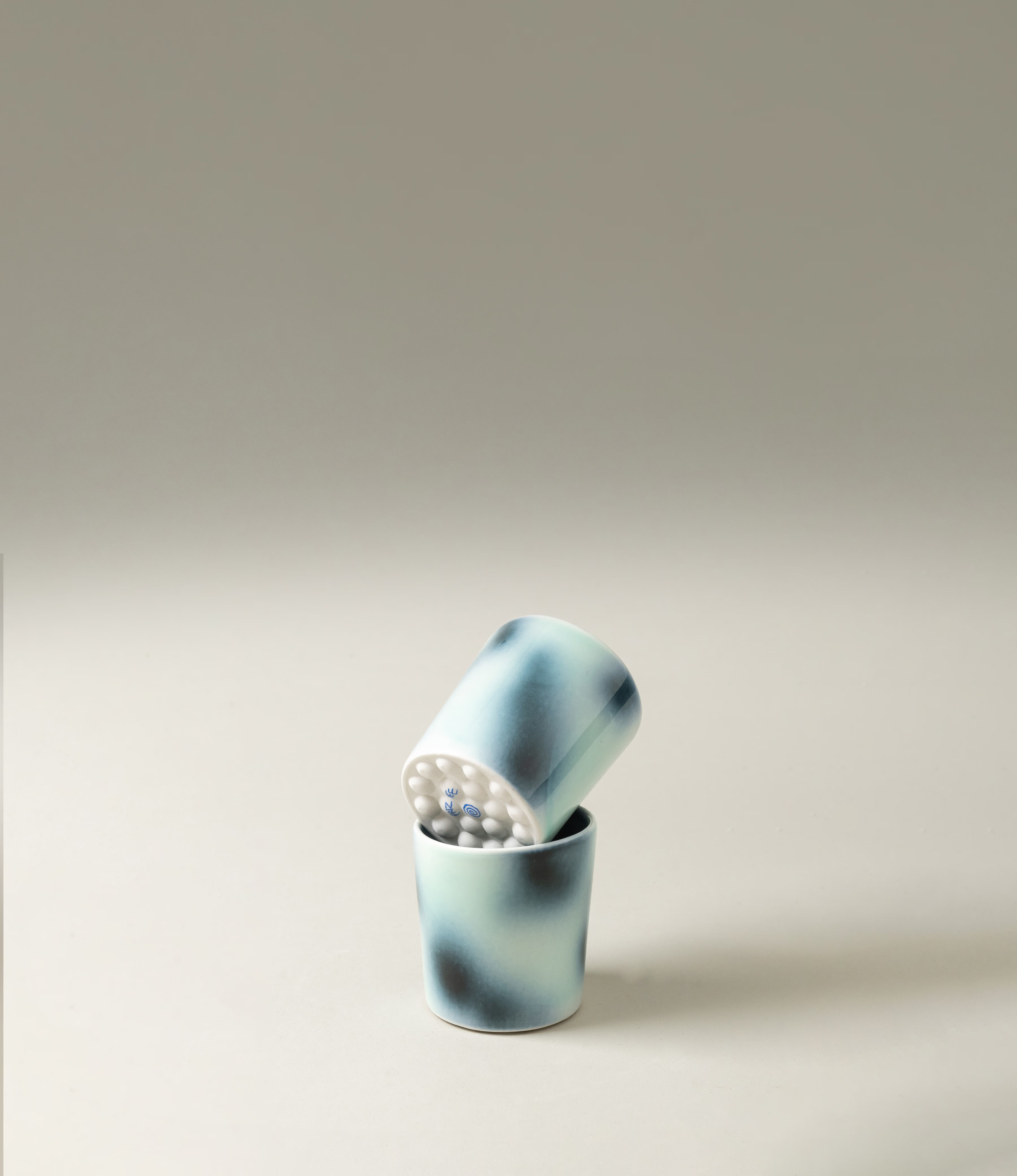 Bulle Cup from Frizbee Ceramics has a unique gradient painted pattern. The product has cold colors like green, dark and light blue. The bottom of the cup looks like it's made of small bubbles.