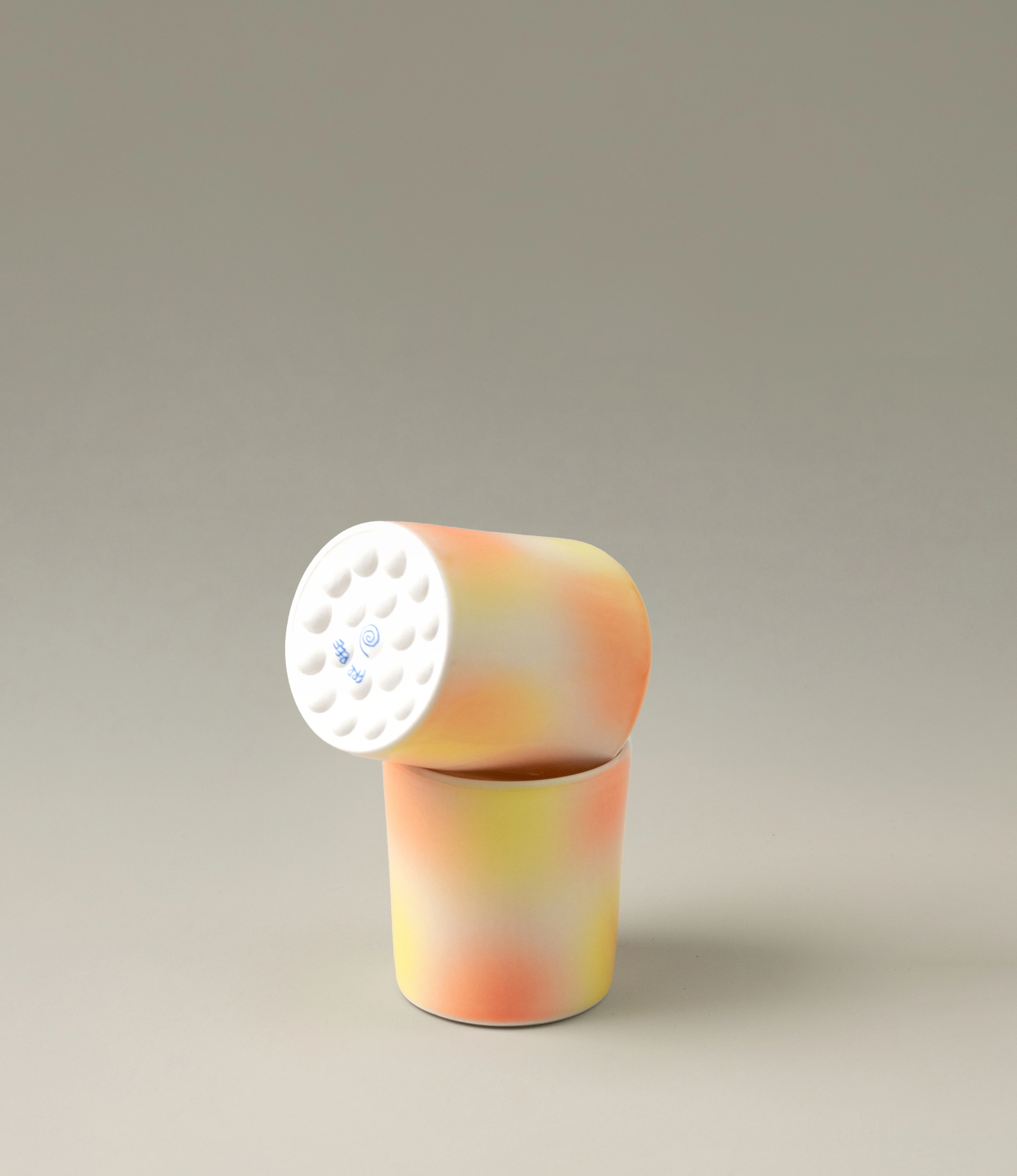 Bulle Cup from Frizbee Ceramics has a unique gradient painted pattern. The cup comes in a set of two and has warm colors like orange, peach and yellow. The bottom of the cup looks like it's made of small bubbles.