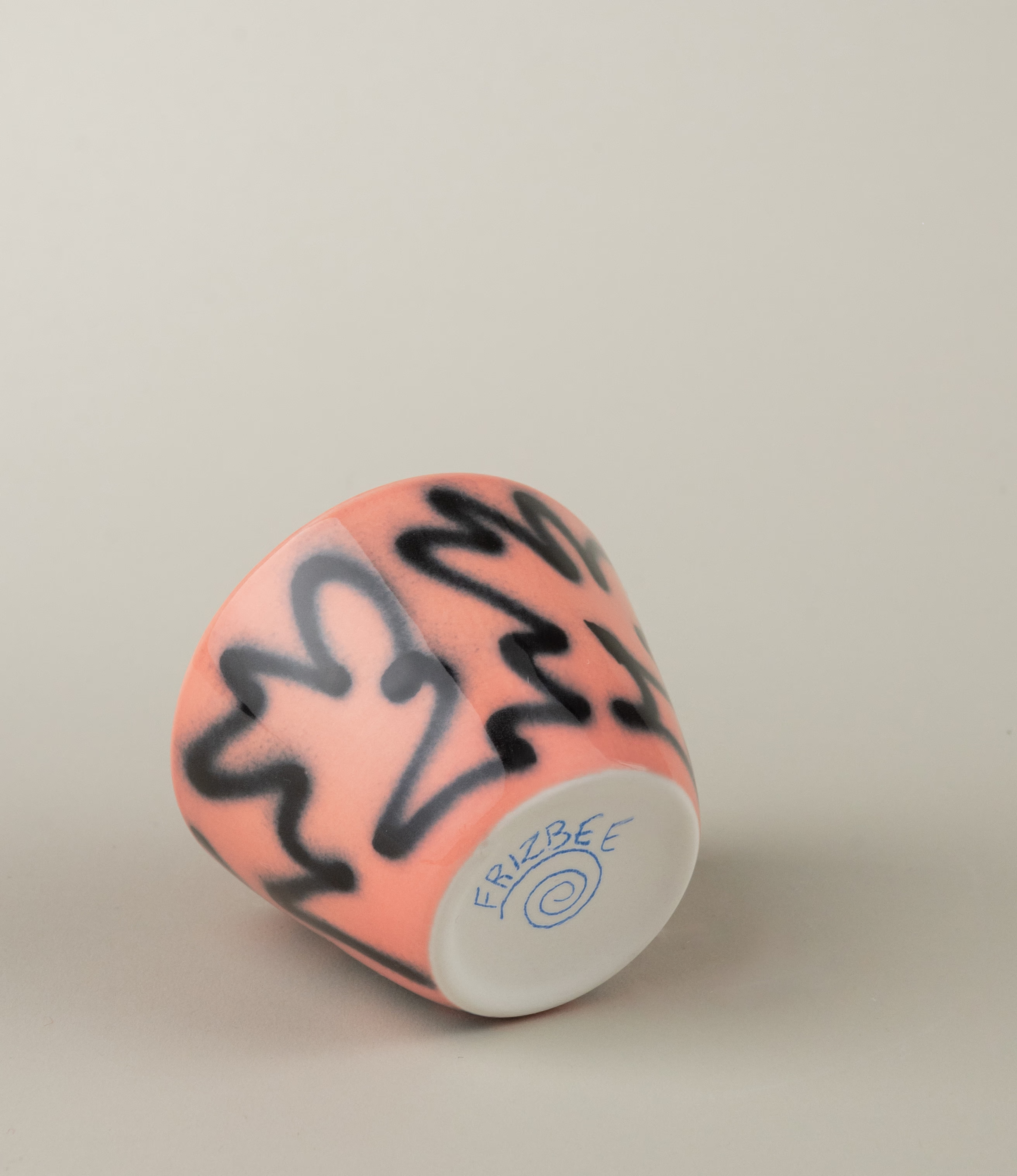 Super Cup from Frizbee Ceramics is a set of two cups. The cups' base is peach with a black graffiti like zig-zag painting on it.