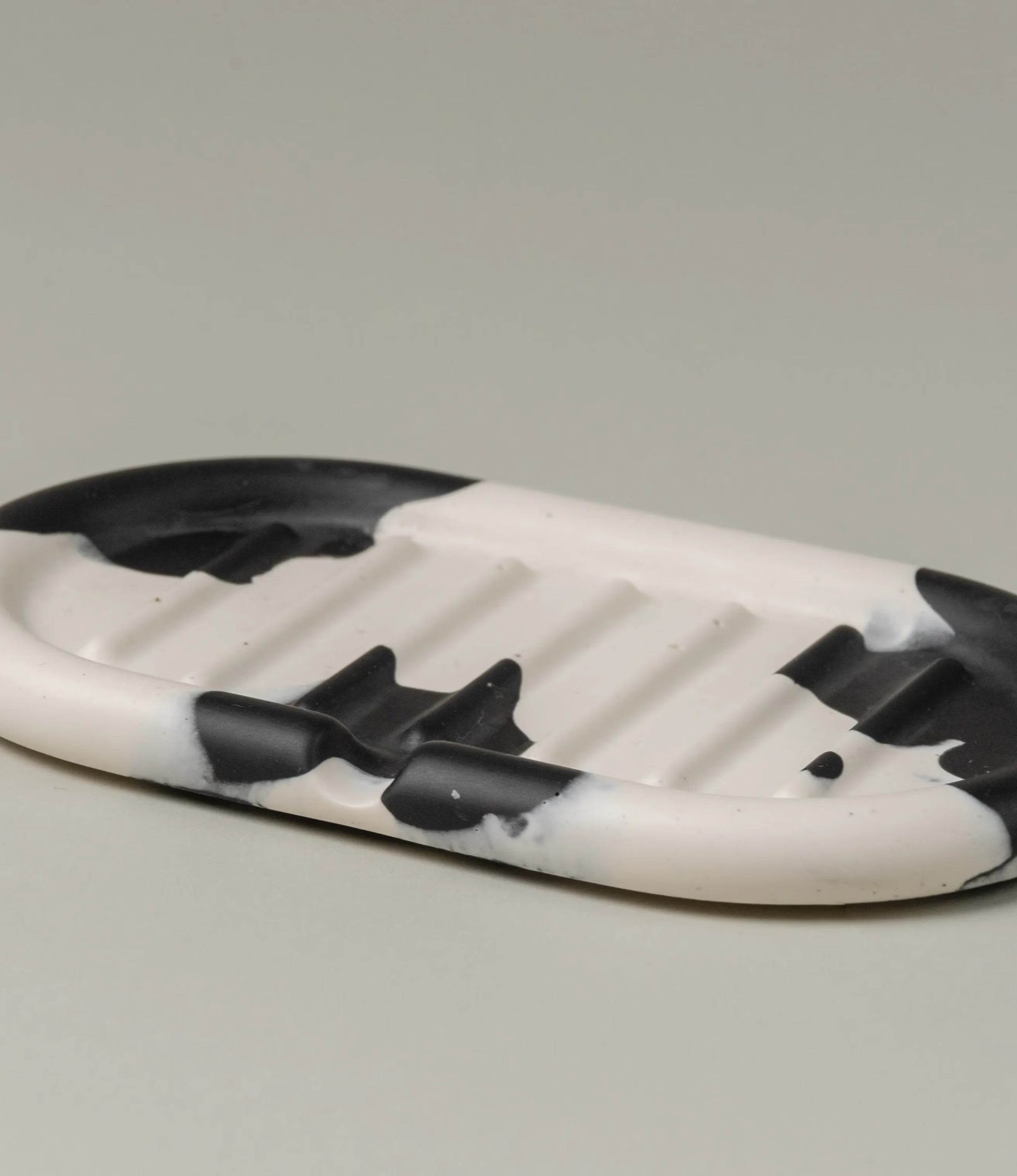 Soap dish from Gritful in a monochrome black and white color. The item has a rounded shape, fits perfectly with our soaps from Azur Natural Bodycare. This picture shows the bottom of the product.