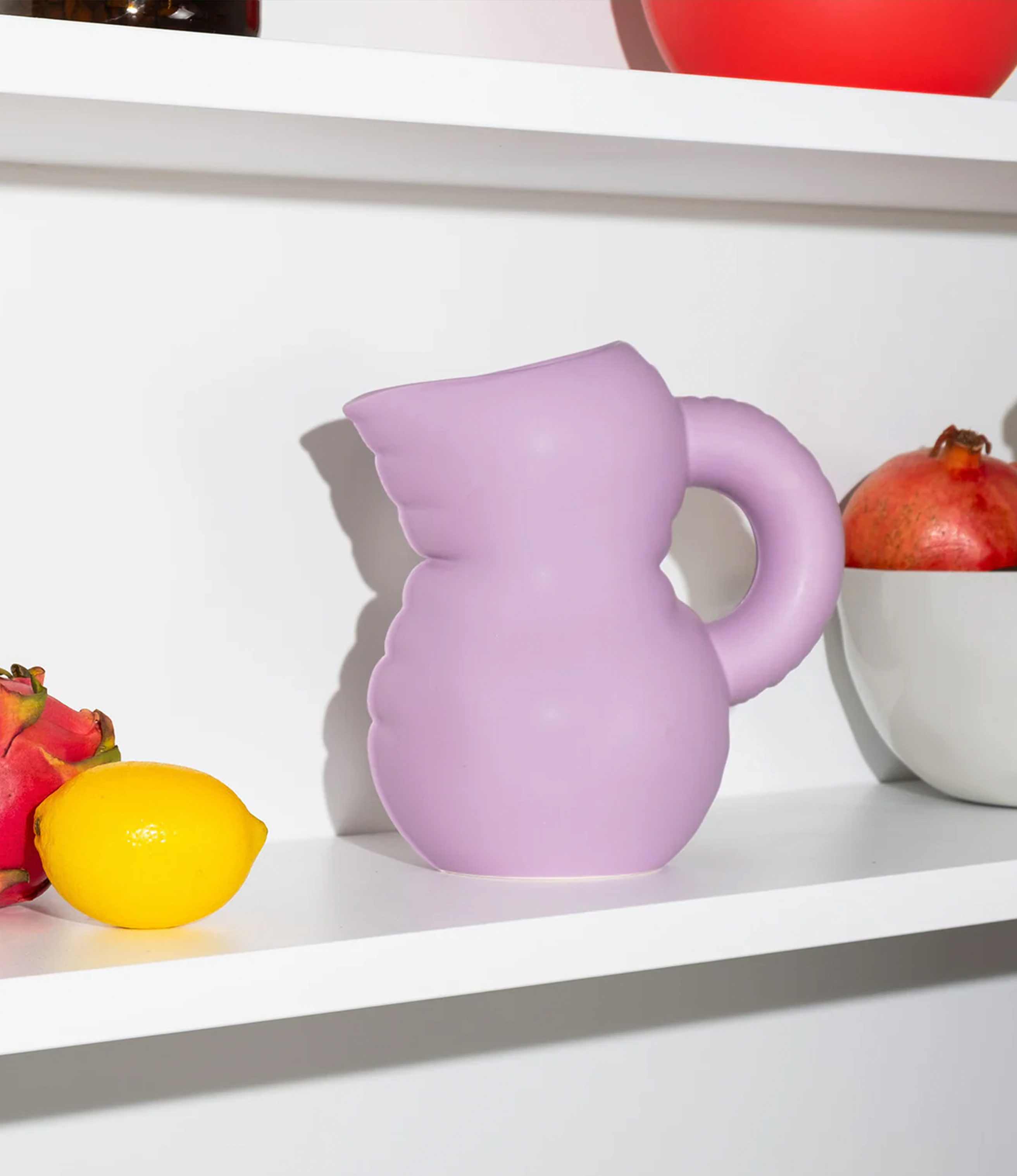 Jug Emily Lila in situation, on a shelf. On the picture there are several other things, mostly vegetables and fruits.