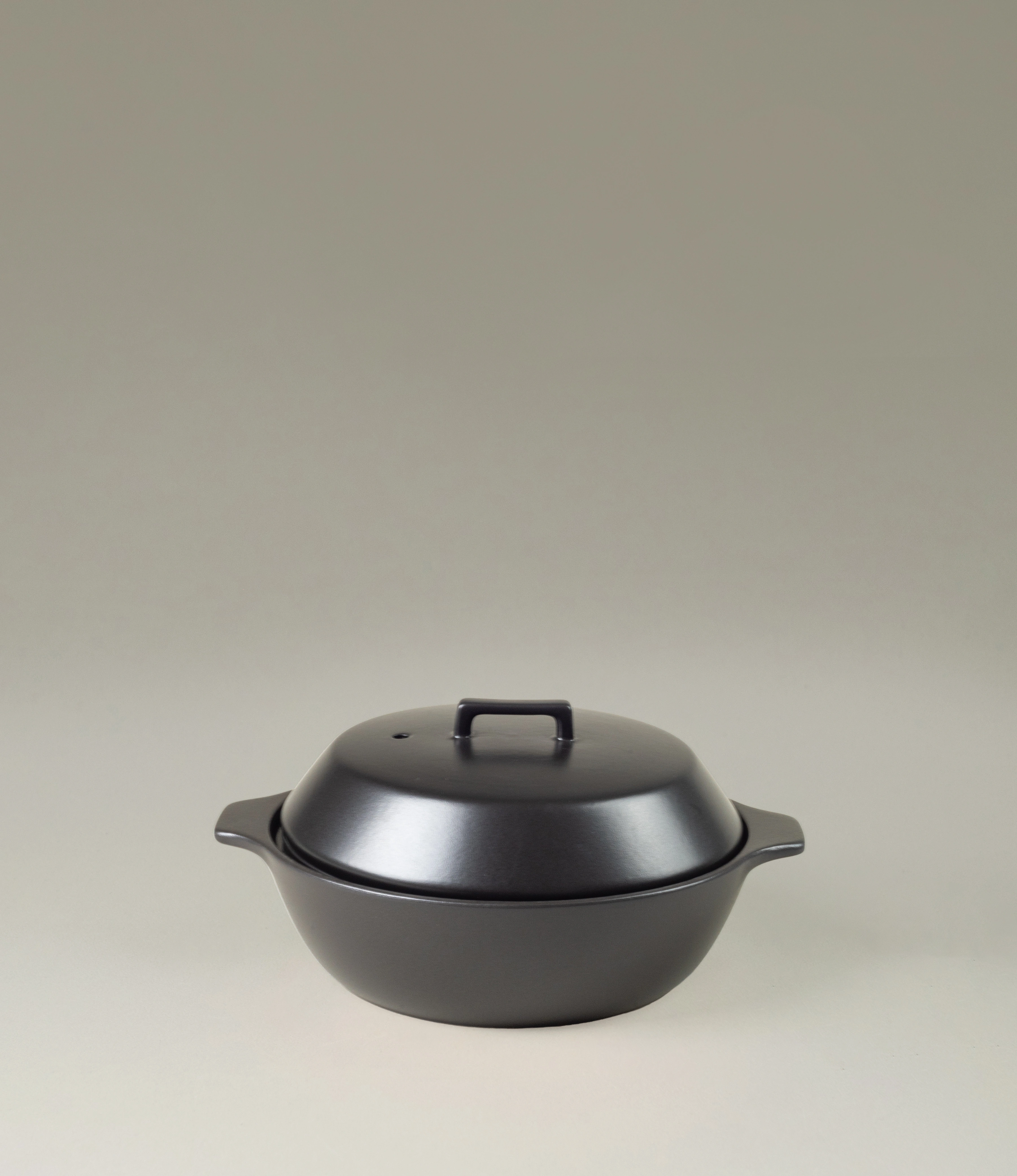Kinto Kakomi Black Ceramic Pot with a minimalist design, featuring a rounded lid and sturdy handles. Perfect for slow cooking and presenting meals with understated elegance.