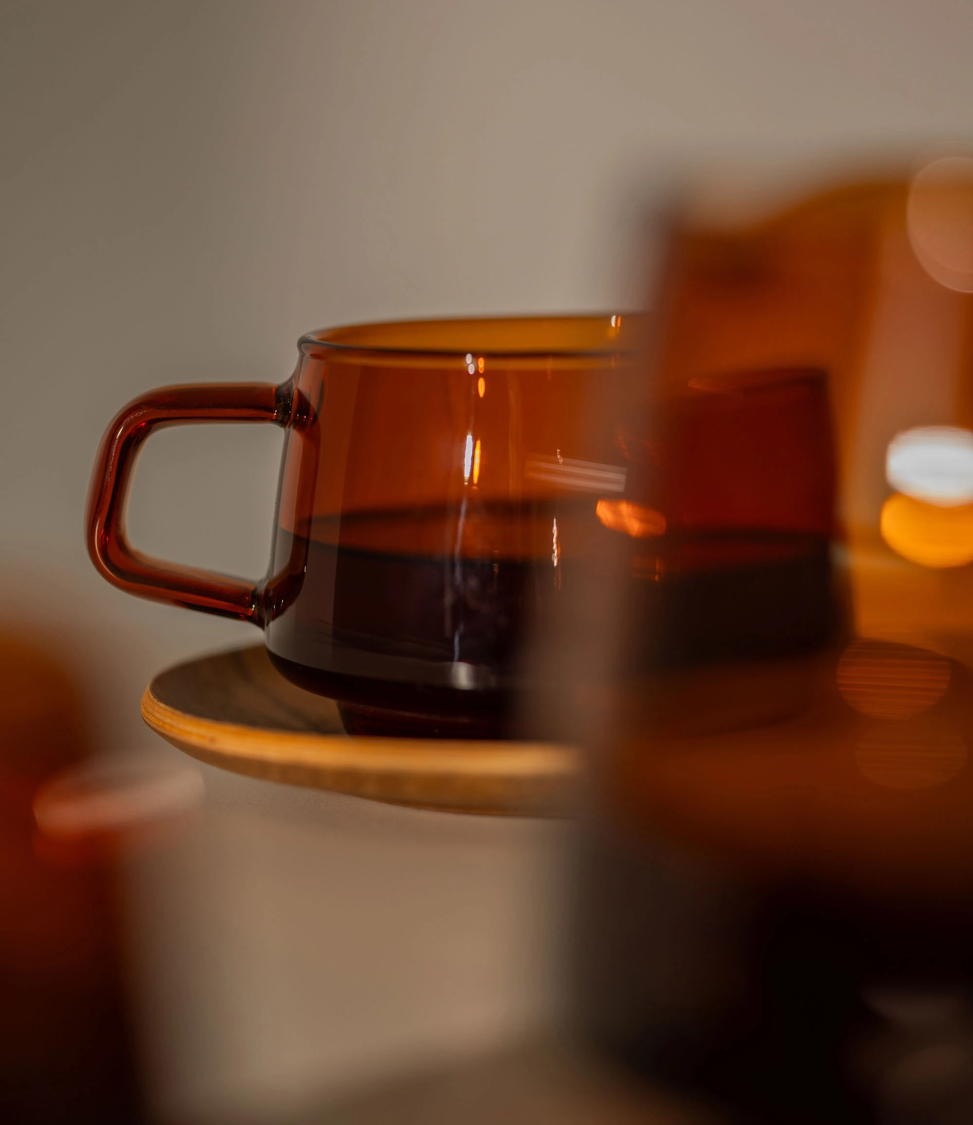 Sepia Cup is a glass mug from the japanese brand Kinto. The item is coming in the popular amber color which fits well the nostalgic shape of the product. The product can hold 270ml of liquid. This is a mood picture, in the front another product is being blurred and the cup is behind it, kind of mysterious.