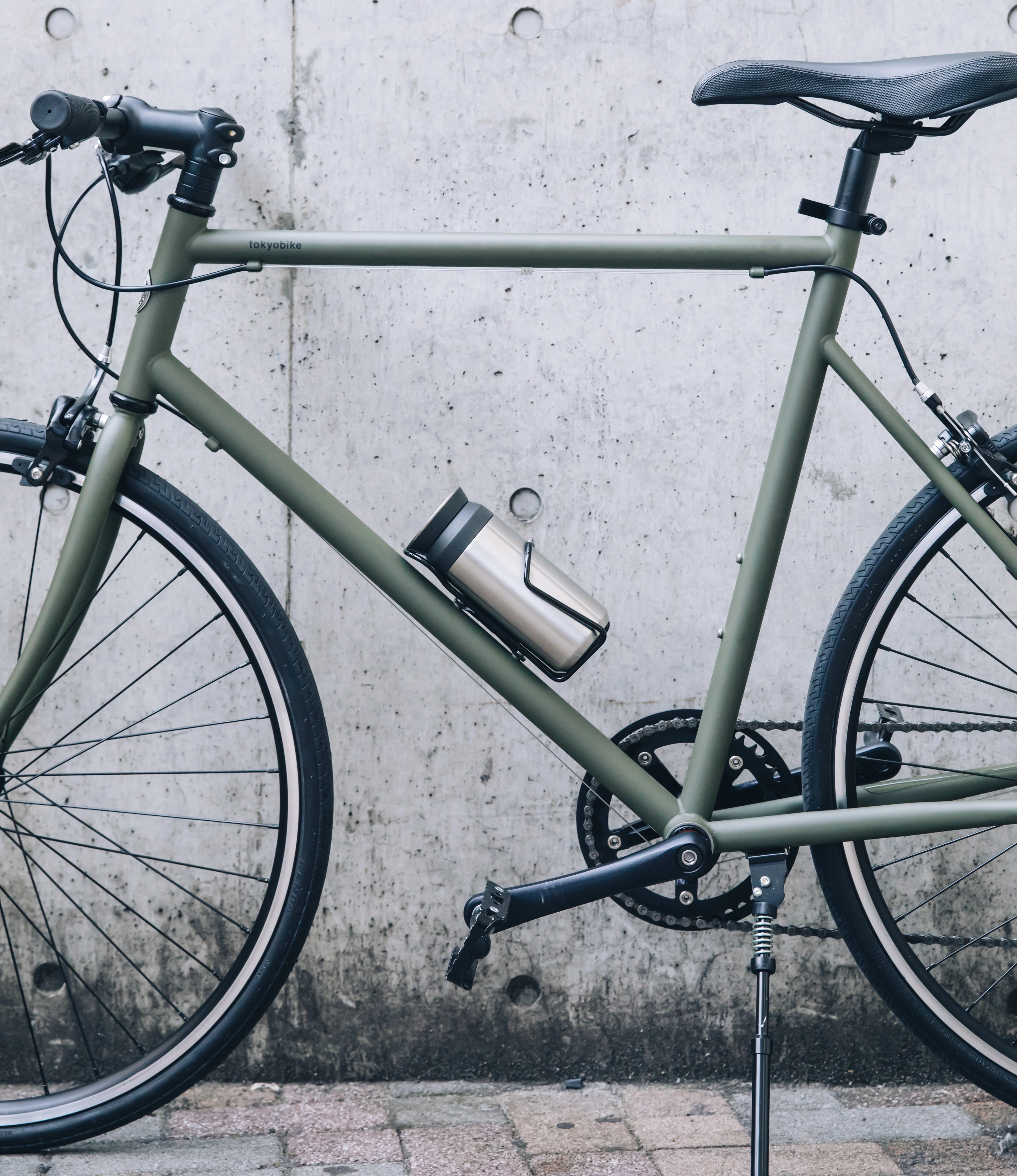 Kinto Travel Tumbler in Stainless Steel color. The product is in use and placed on a green bike.