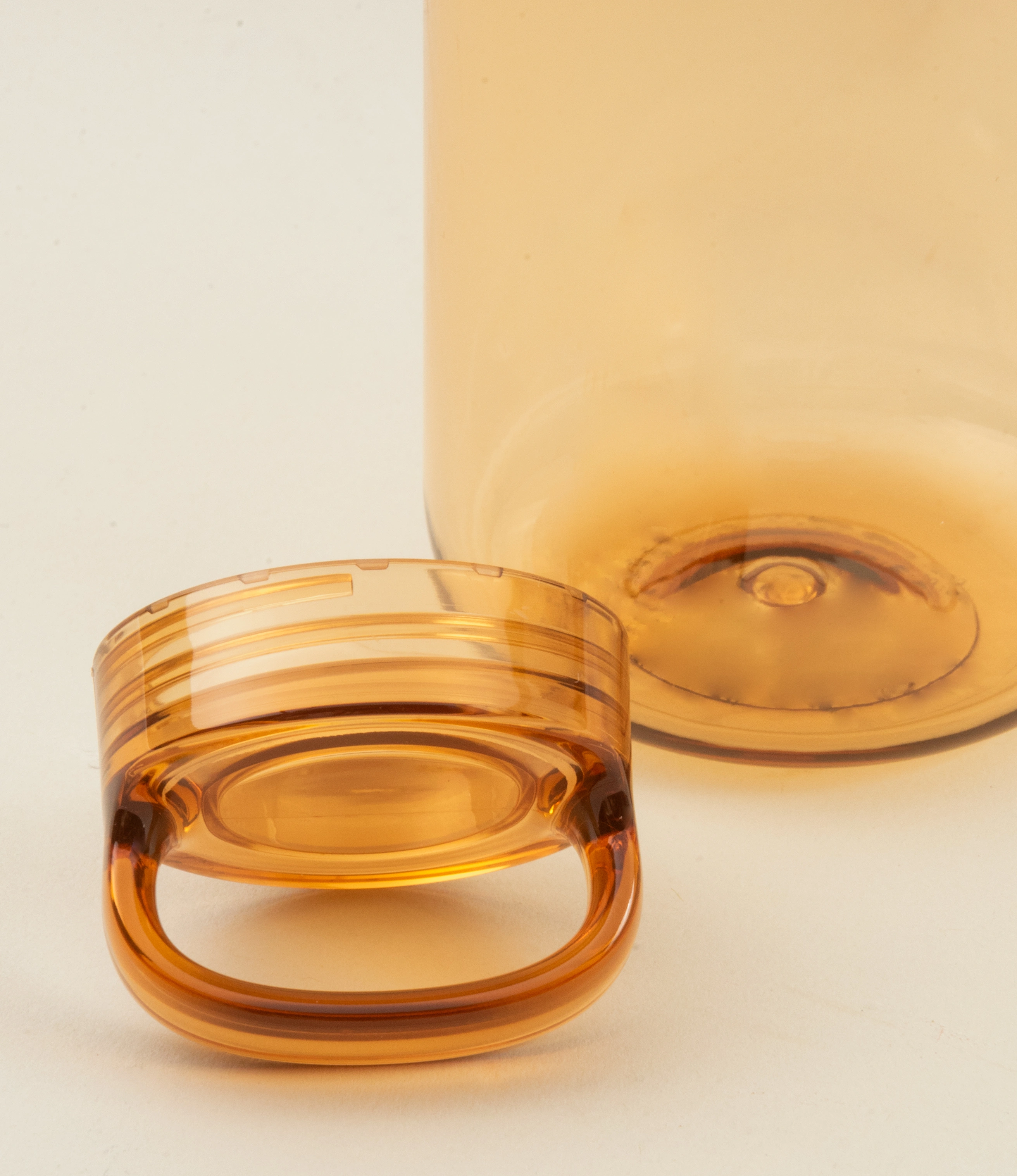 Close-up view of the amber-colored water bottle's top, highlighting the ergonomic integrated handle and the smooth, translucent plastic material. The design emphasizes functionality and a modern aesthetic.
