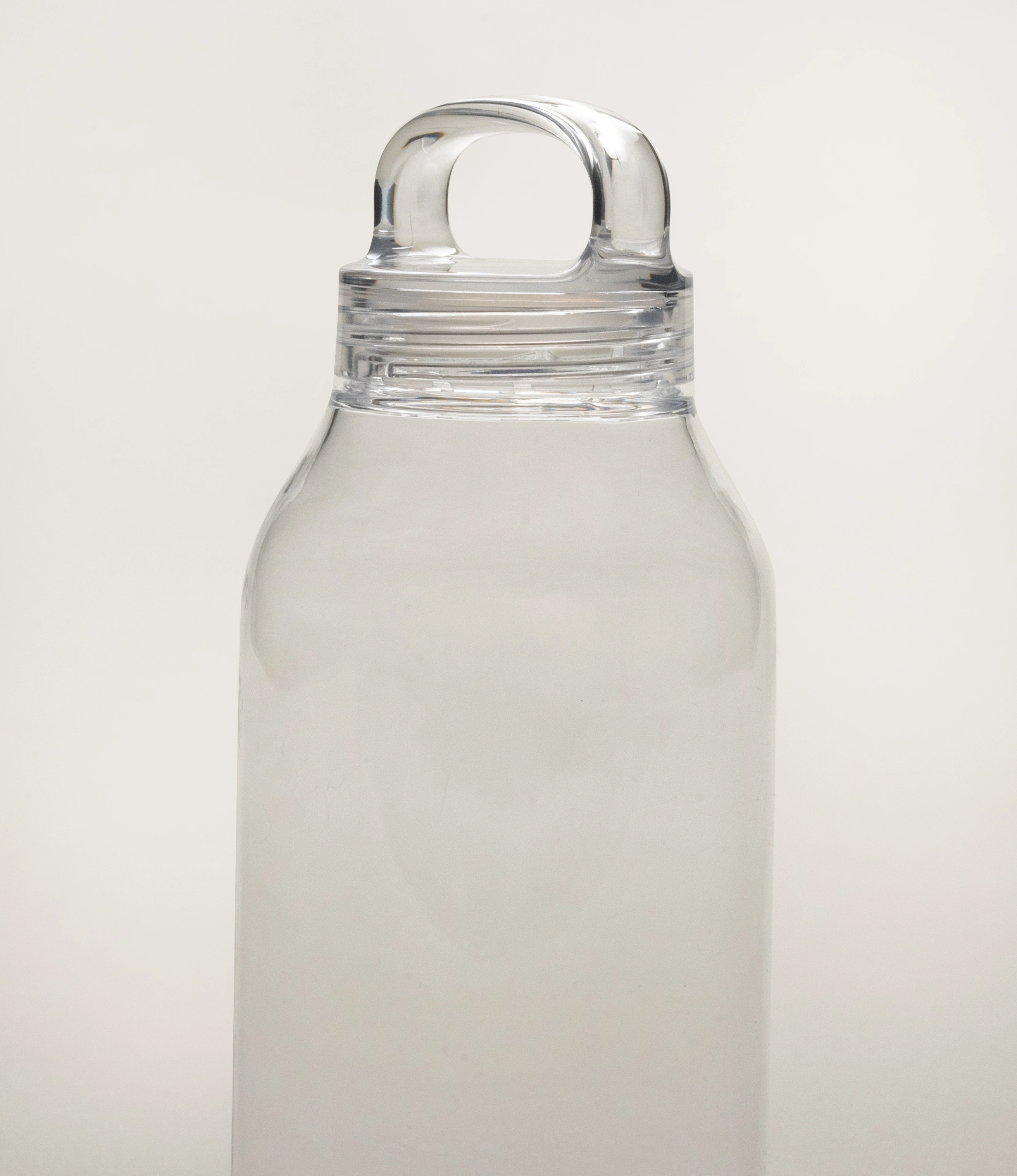 Close-up of the upper section of a clear Kinto water bottle with an attached loop handle cap. The bottle's simple and transparent design stands out against a plain, light background, showcasing its minimalist style.