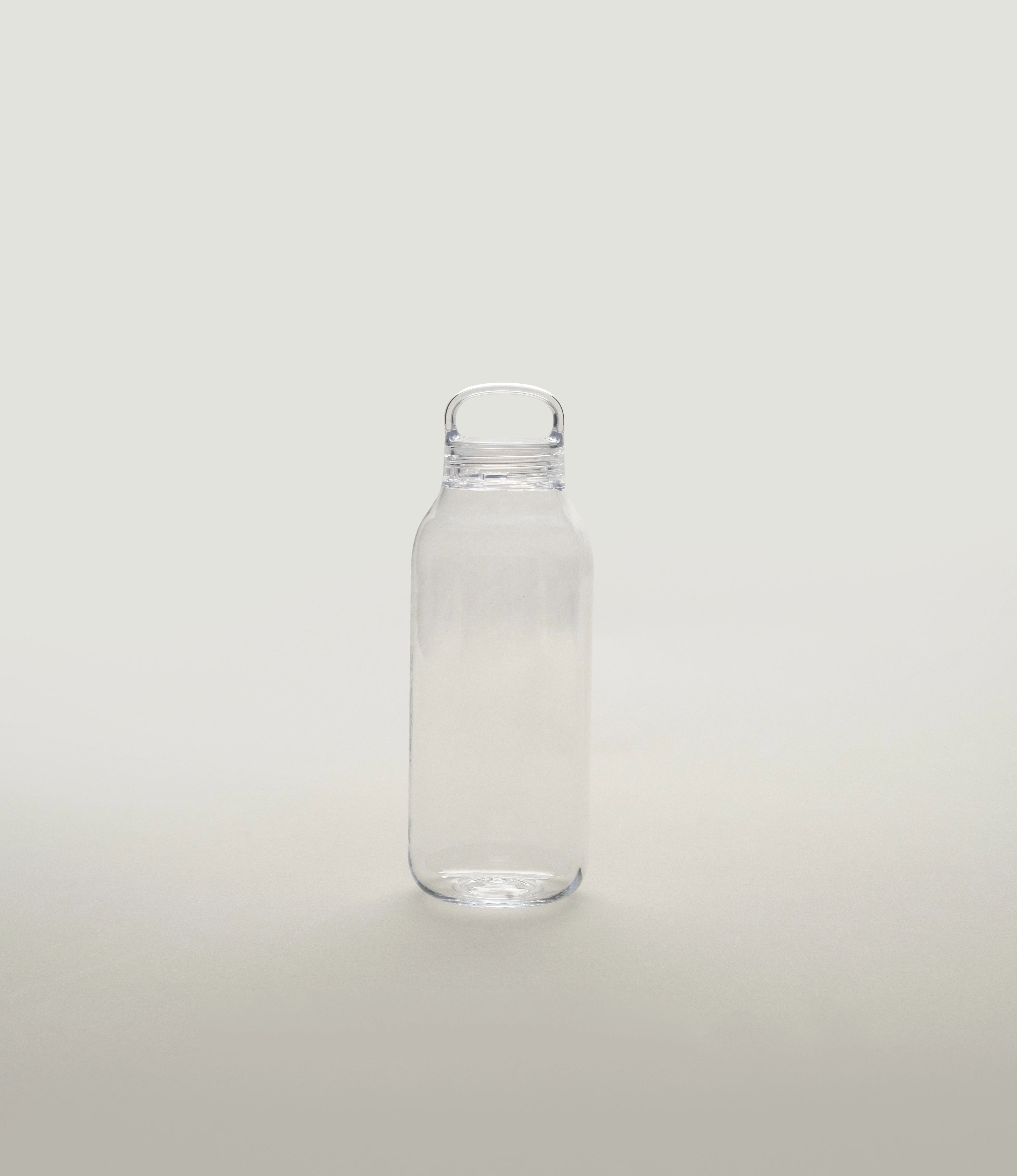 Minimalist clear water bottle with a simple loop handle, standing upright on a light neutral background.