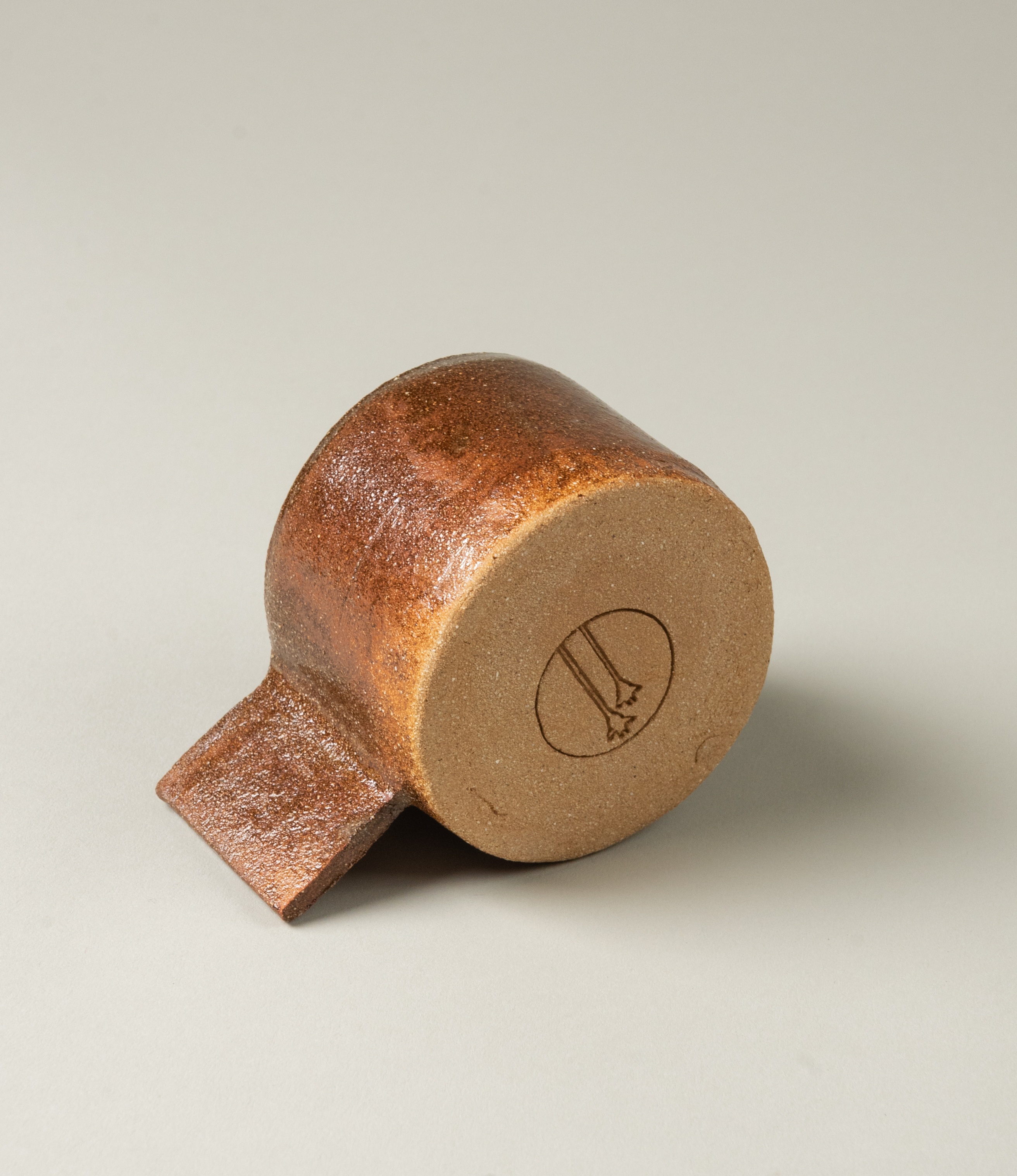 Ceramic cup from Manamo Cup. The item comes in the soothing earthy coffee color. The handle has an unusual rectangle shape which makes the modern touch to the natural tone and texture. The bottom of the product has the debossed logo of Manamo Cups.