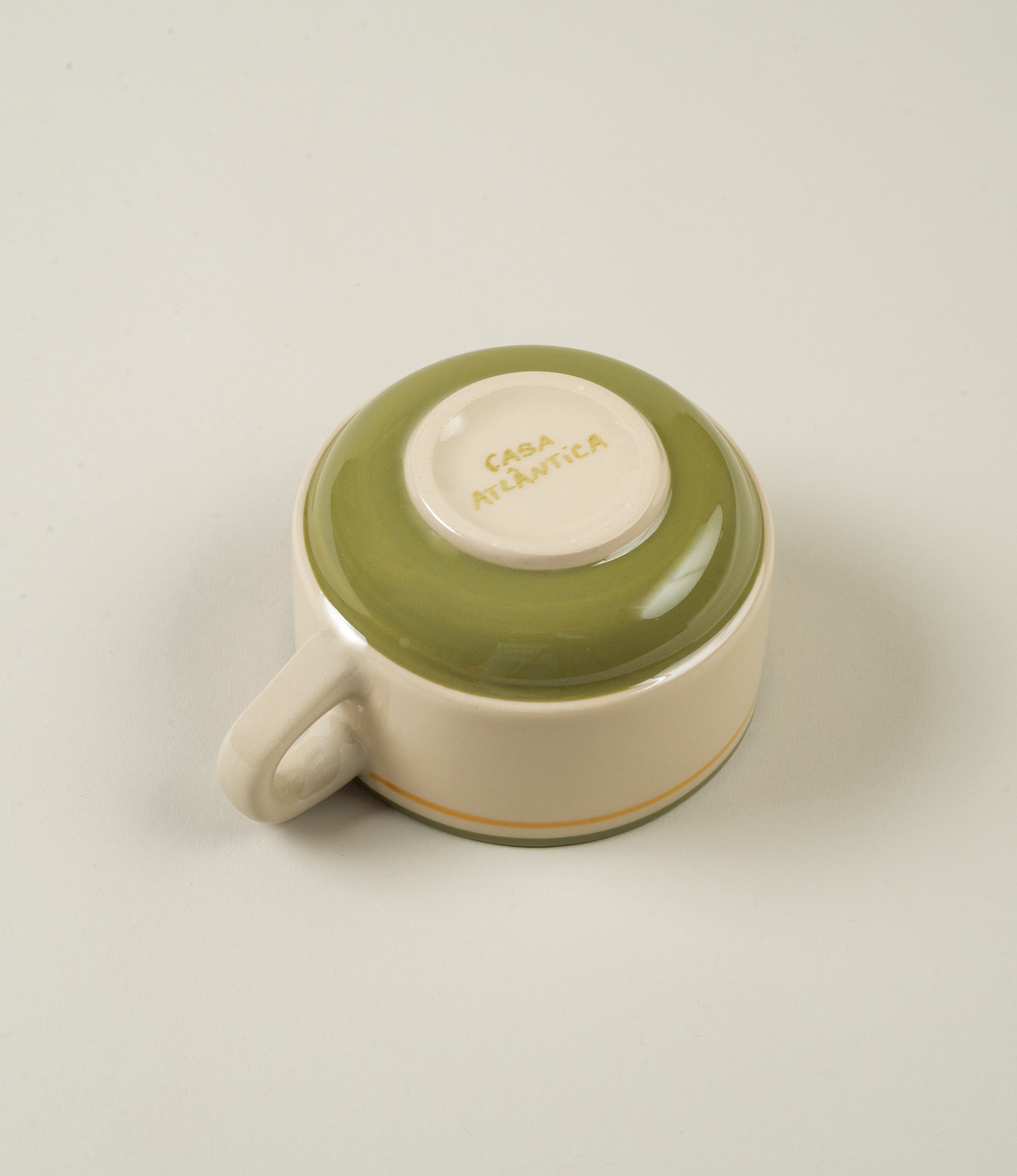 Base view of Casa Atlântica green ceramic coffee cup showing glazed bottom and hand-lettered maker’s mark.