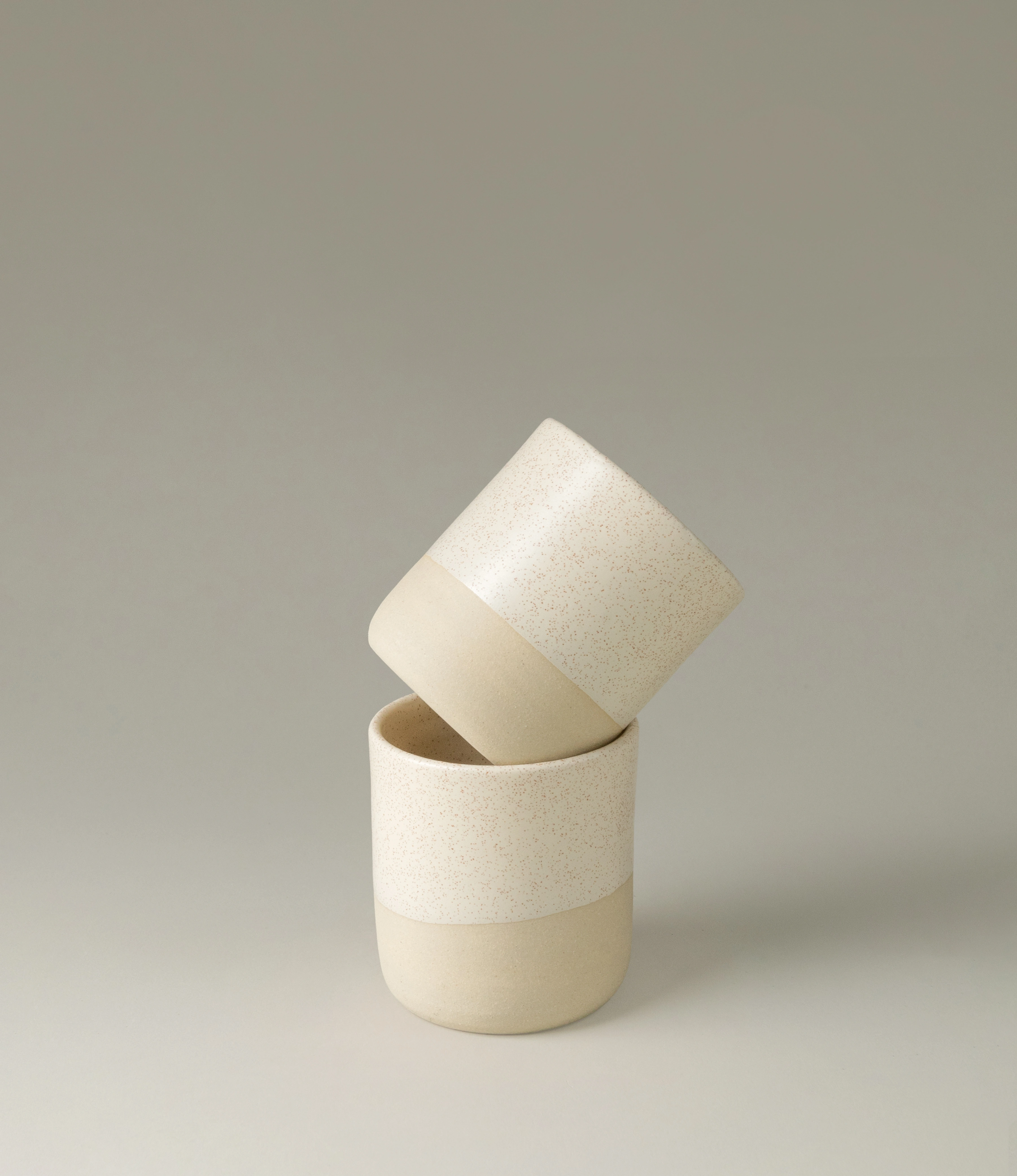 Cream Cup from Ocactuu is a set of two beige ceramic cups. The bottom of the cup has a different glazing and a slightly darker color. The eggshell pattern of the product enhances the minimalist handmade shape.