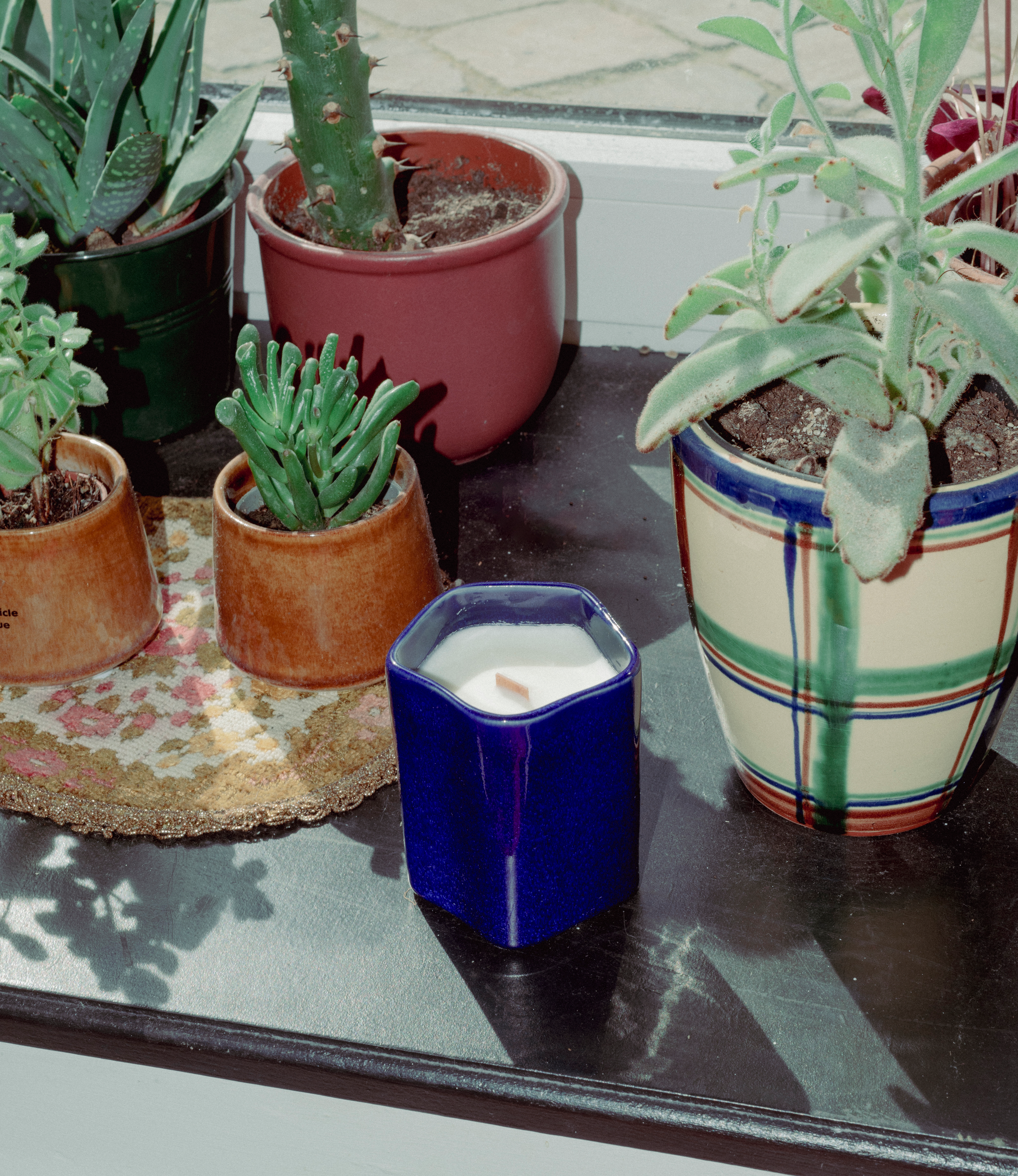 A scented Wax Candle designed by Ocactuu. The candle has an amber scent and it comes in a glossy dark blue ceramic. The material has a subtle spotted texture. The candle wick is made of wood for a more natural feeling.  