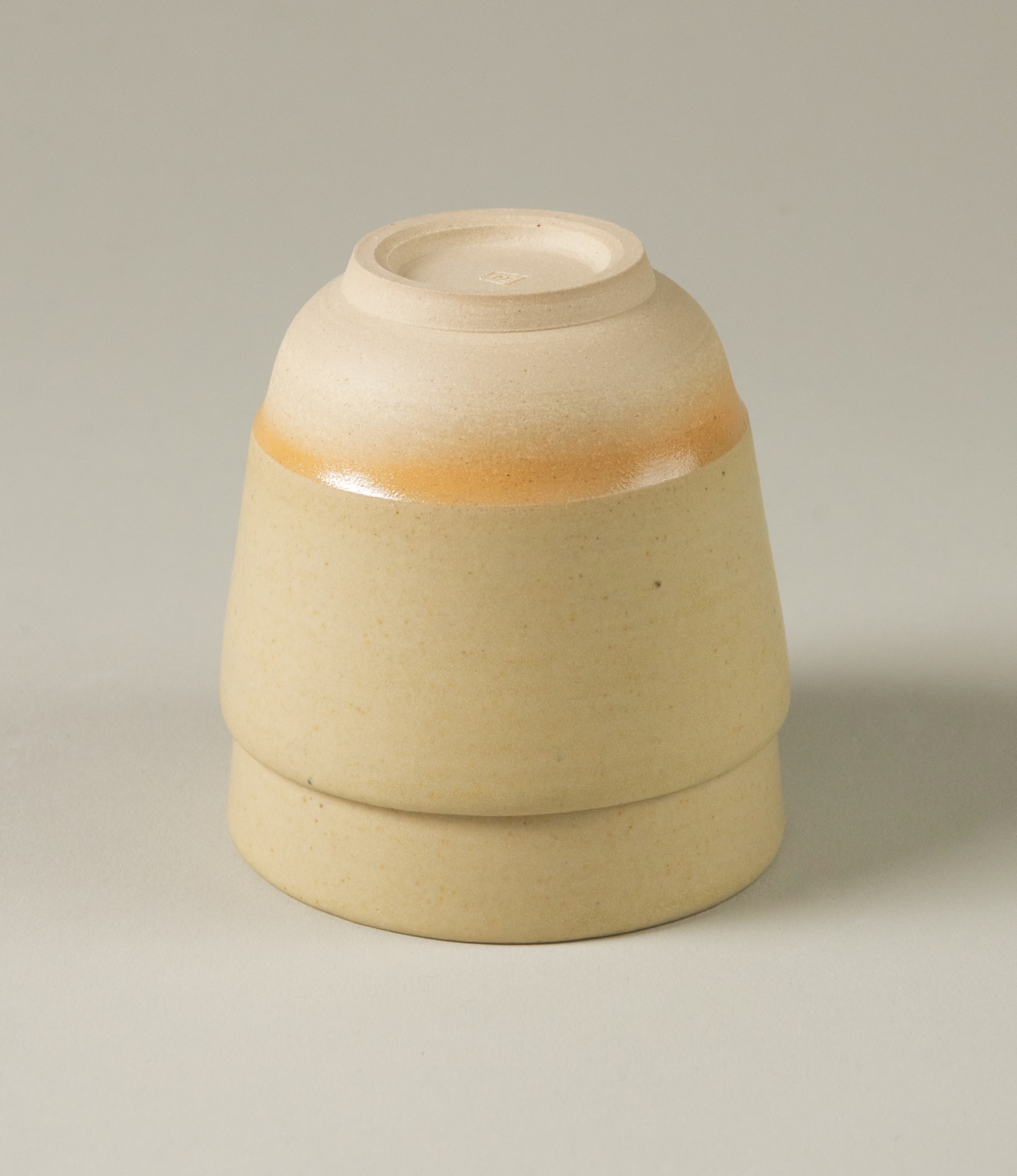 This cup set is handcrafted by Omni Ceramics. The two small cups are wearing a gradient orange color ring on the natural beige base. 