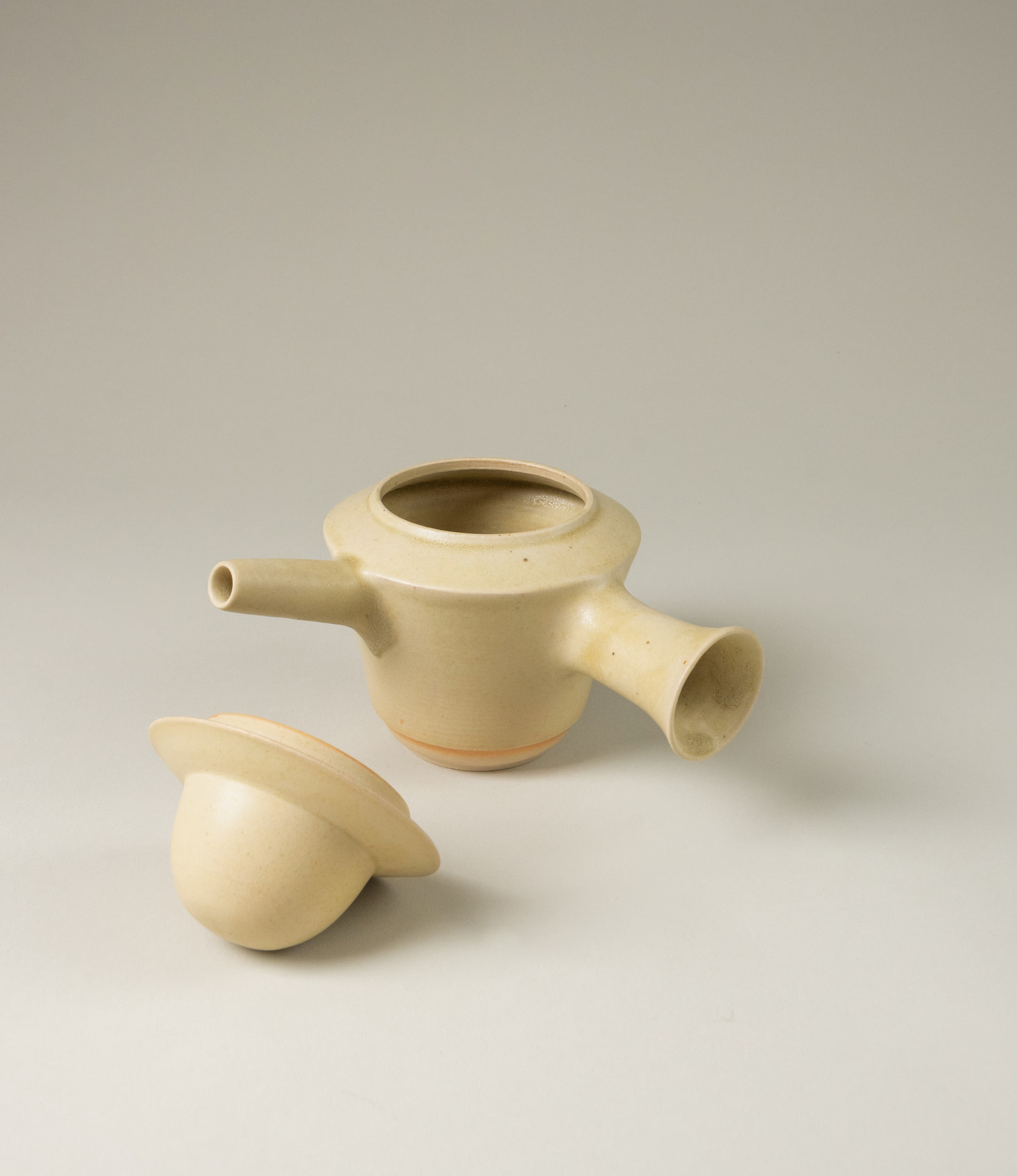 A special teapot from Omni Ceramics. The product adds a spice to the Omni tea collection. The lid of the teapot resembles a hat. The item comes in a light beige color, and with the unique painted orange gradient ring on the lower part of the product.