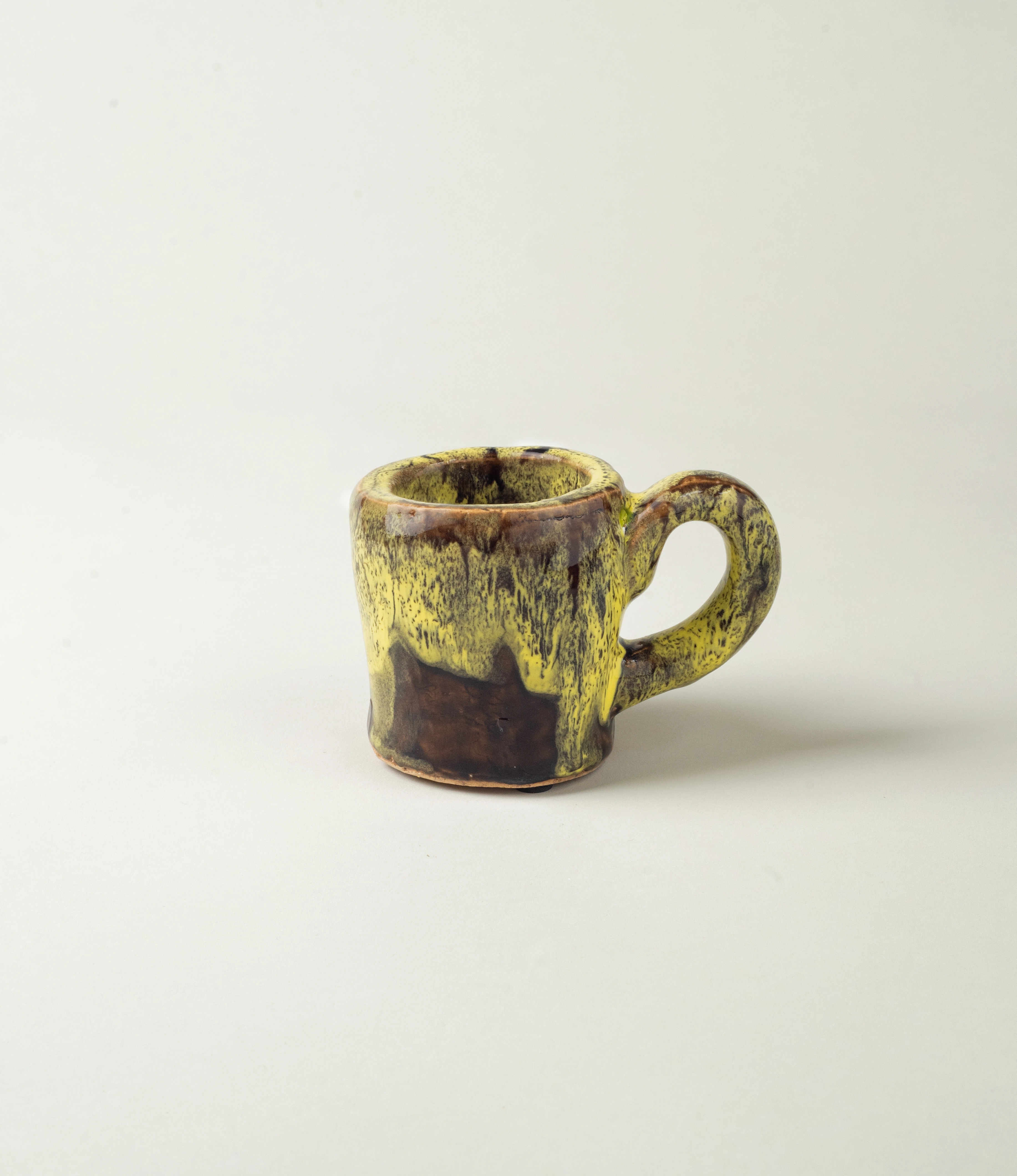 Cafeflamengo decorative cup from Serax. The cup is not suitable for drinking from it but can be perfect to store items on your desk. The cup has a special glazing with a dripping effect on it. The base of the cup is brown and the dripping is yellow. The item is handmade.