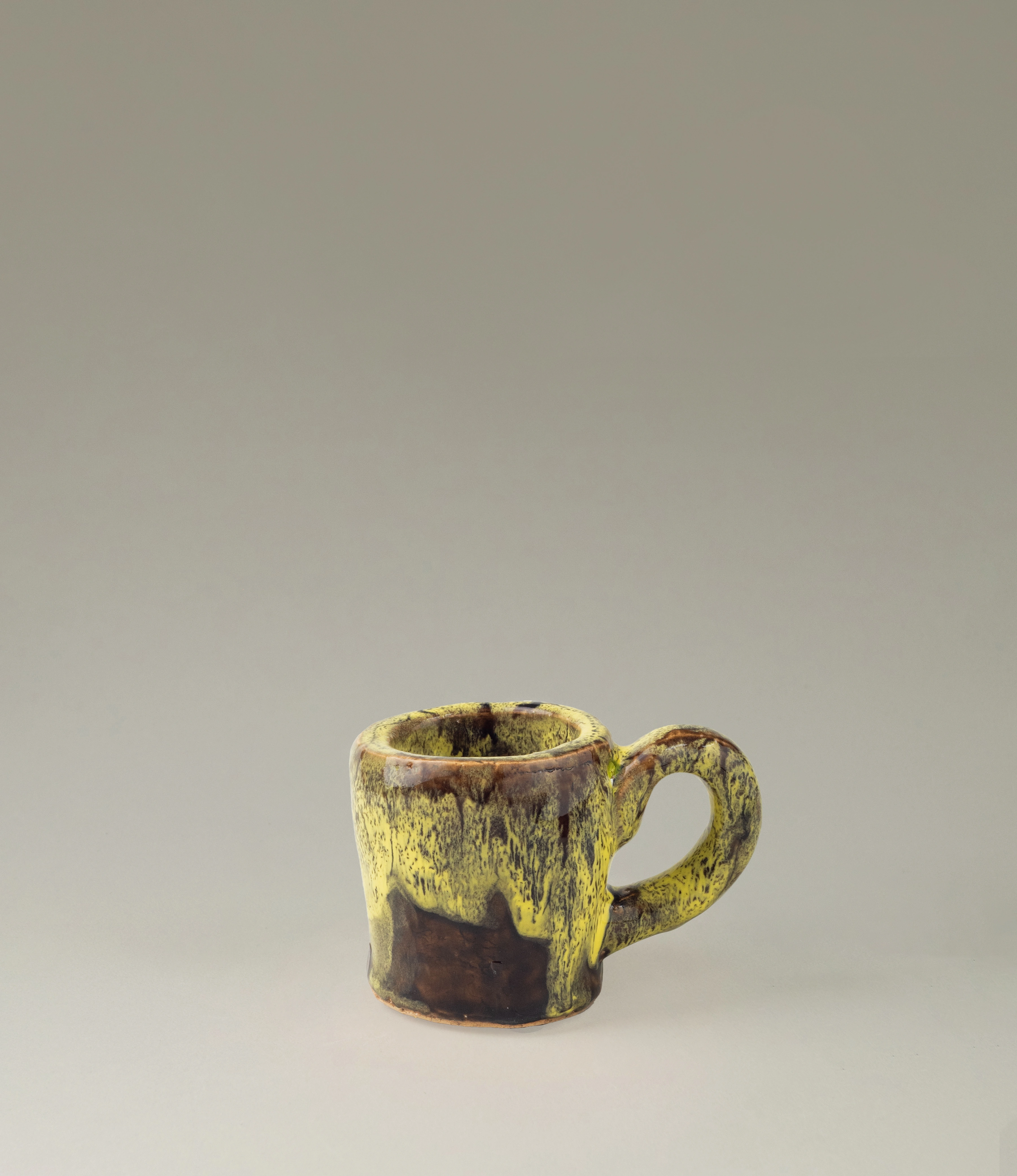 Cafeflamengo decorative cup from Serax. The cup is not suitable for drinking from it but can be perfect to store items on your desk. The cup has a special glazing with a dripping effect on it. The base of the cup is brown and the dripping is yellow. The item is handmade.