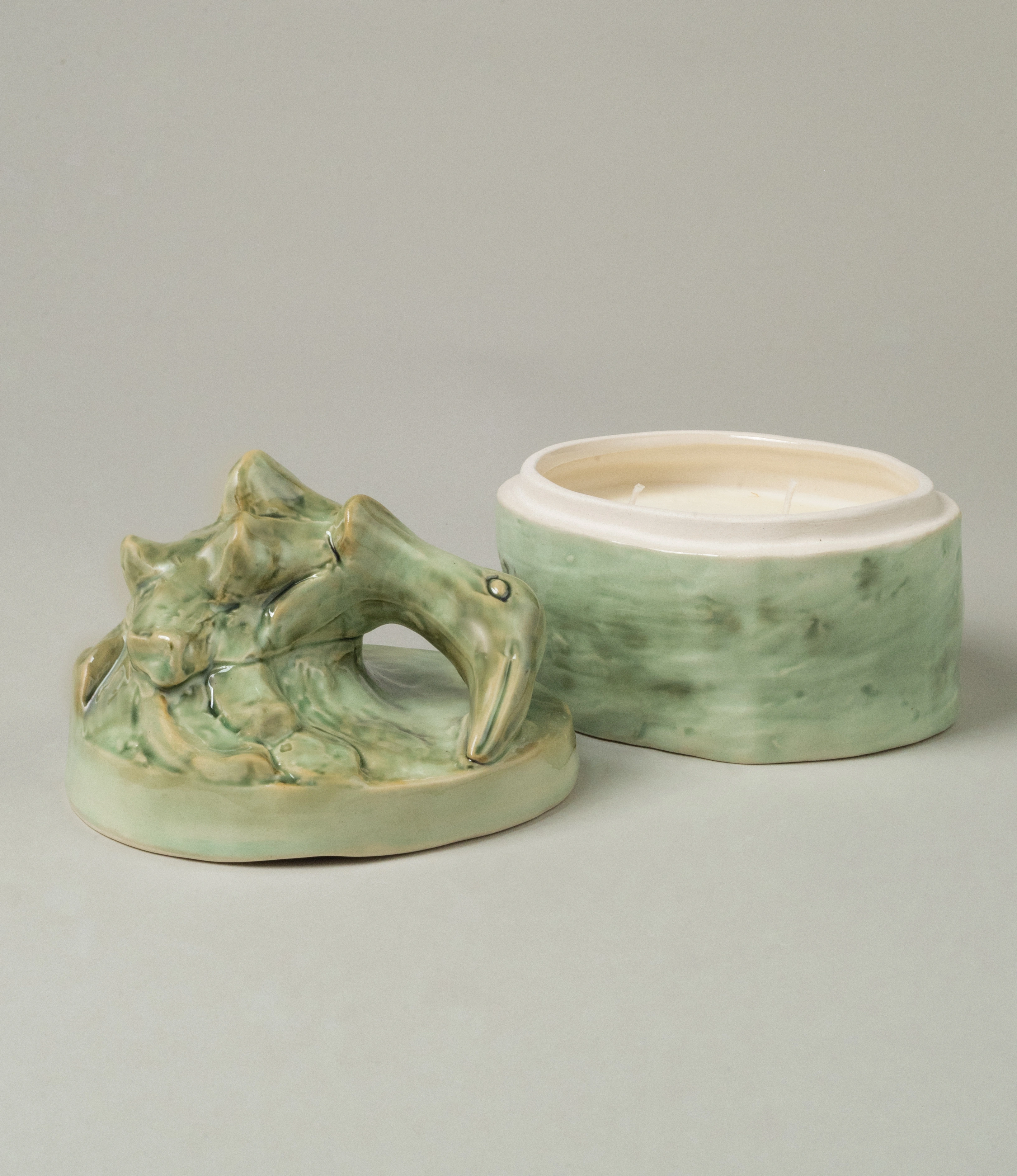 Serax Green Sonata medium-sized candle with its unique ceramic lid removed, revealing the white wax inside the green ceramic container, all set against a neutral background.