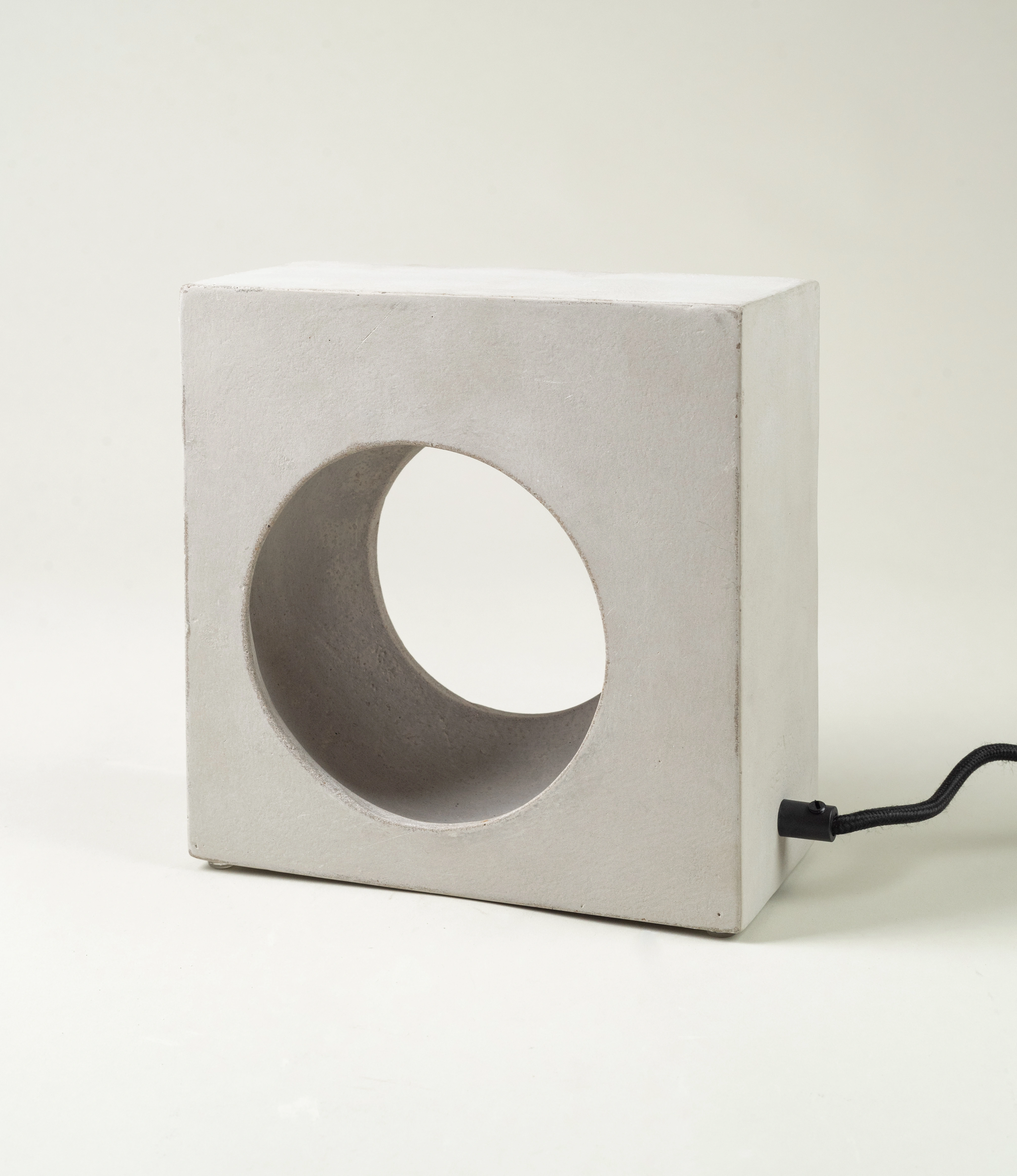 Serax Flastair Concrete Lamp — a minimalist lighting piece with a sculptural, circular cutout. Its raw concrete finish adds a touch of industrial elegance to modern interiors.