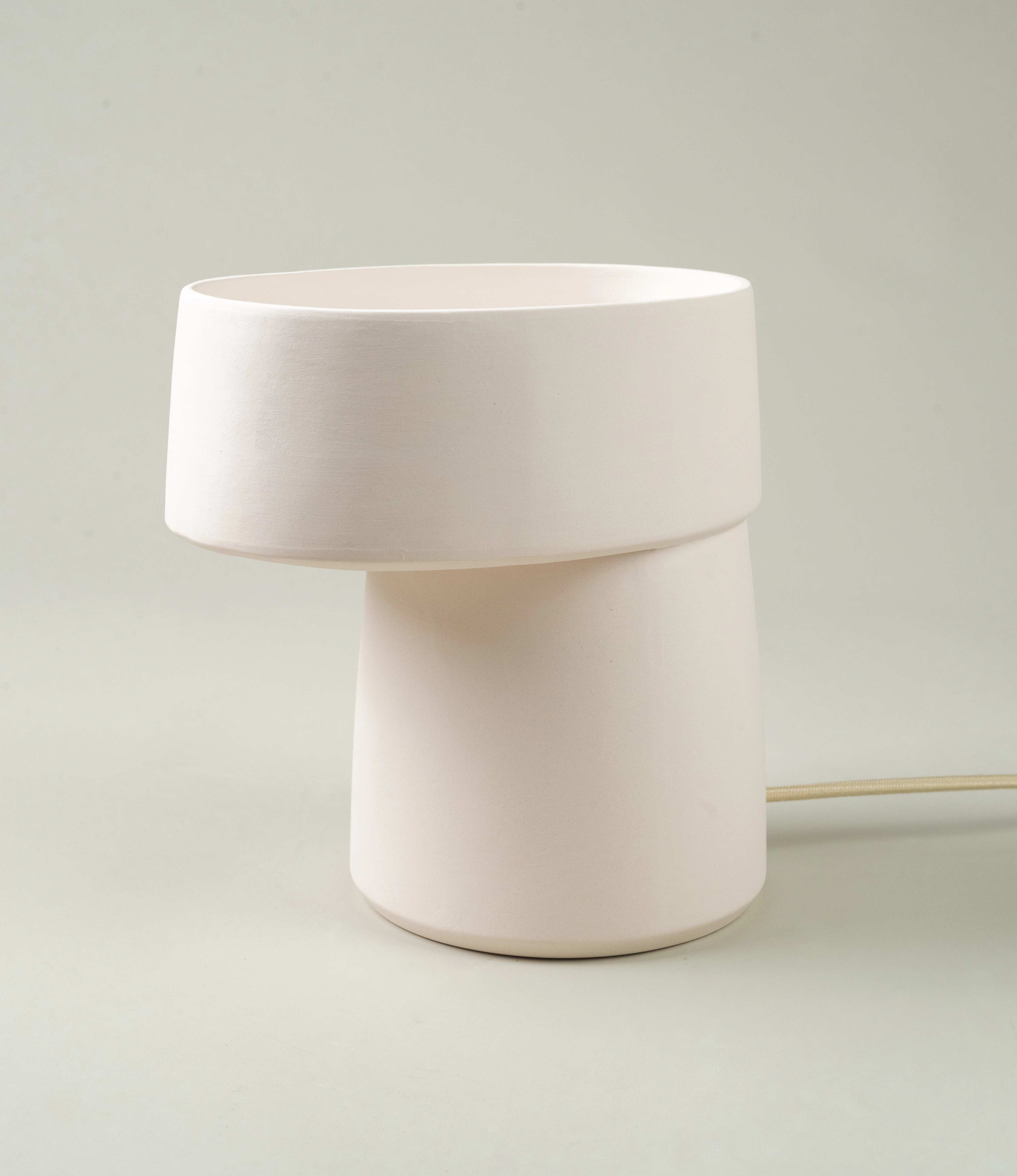 A sleek, off-white ceramic table lamp with a modern, sculptural design. Its clean lines and understated elegance make it a perfect addition to contemporary or minimalist interiors.
