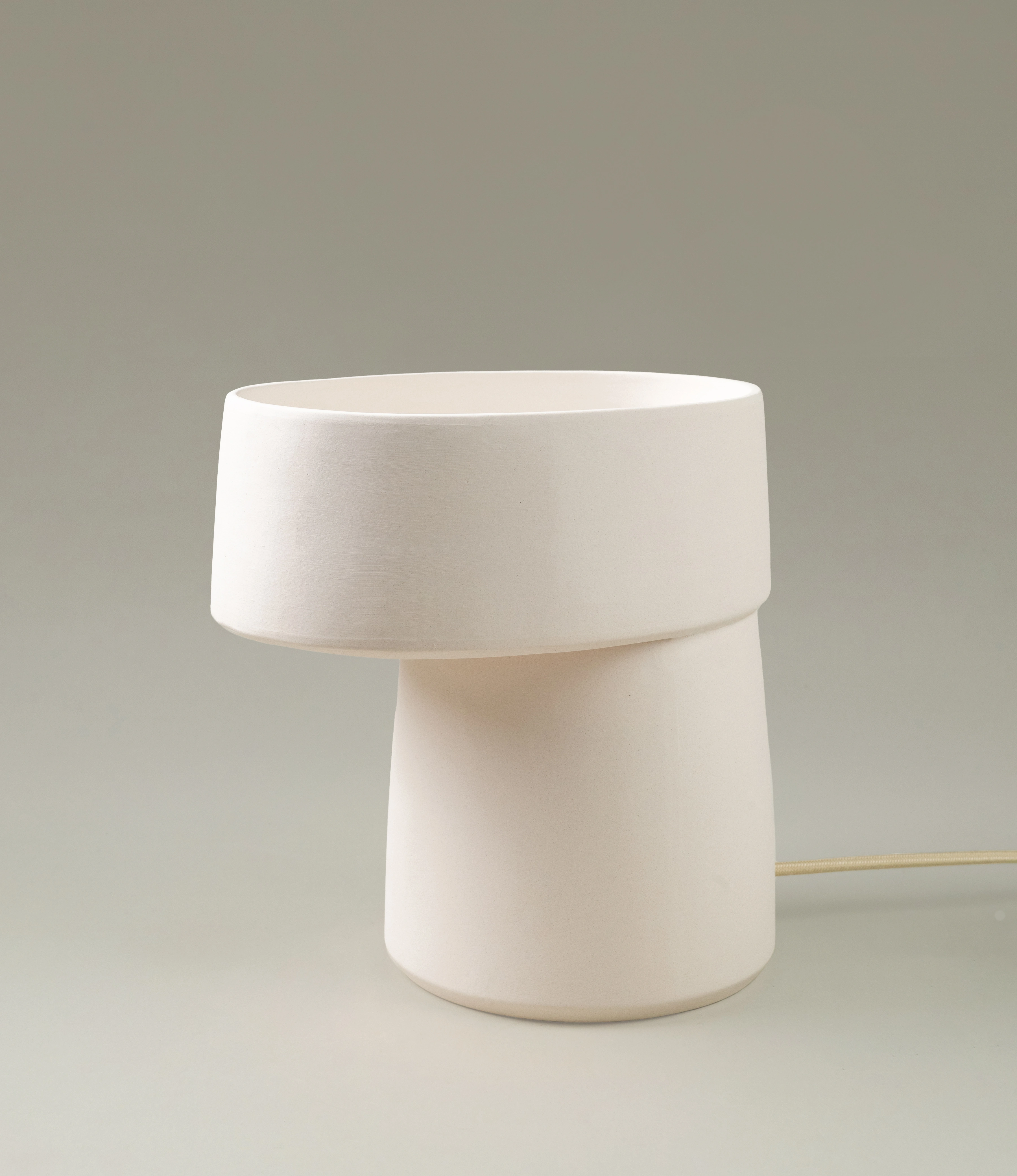 A sleek, off-white ceramic table lamp with a modern, sculptural design. Its clean lines and understated elegance make it a perfect addition to contemporary or minimalist interiors.