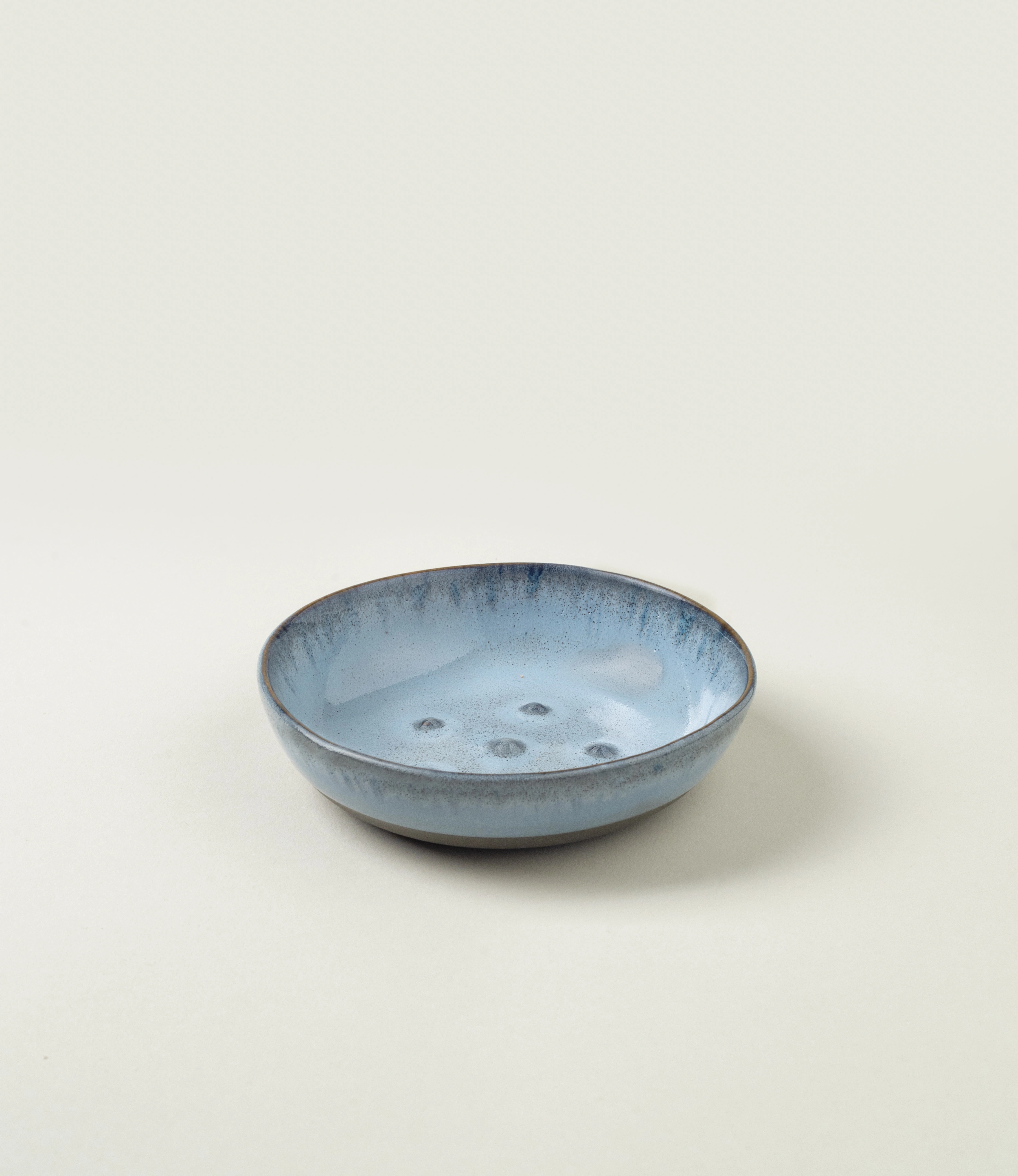 Blue Soap dish from Serax. The round item is made of ceramics and have a blue glazing with a grey unglazed matt area on the bottom. On the edges it has a grey rim.