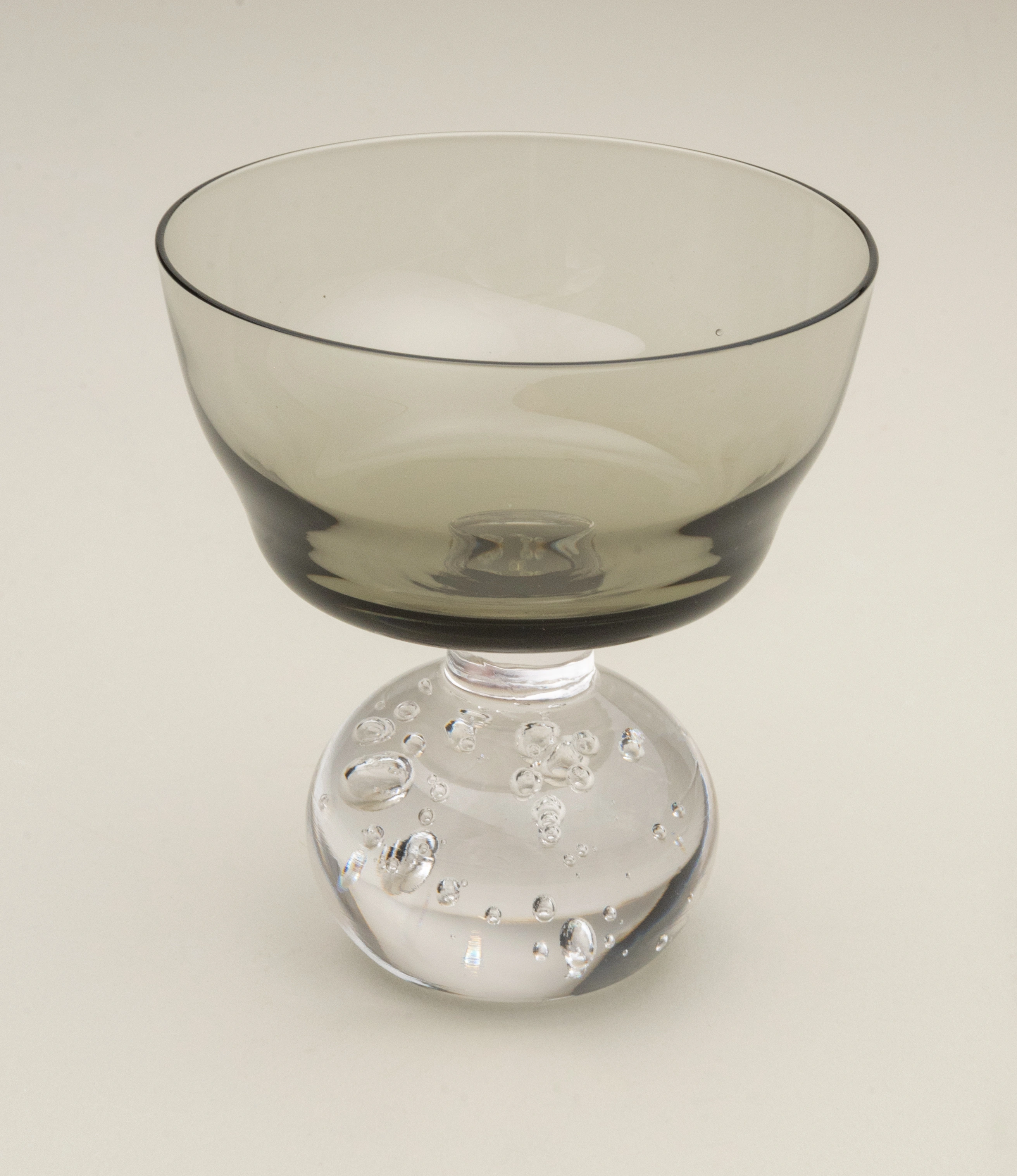 Serax Stem Glass featuring a smoky-tinted bowl and a clear, textured spherical base. A refined and artistic design perfect for serving cocktails or desserts in style.