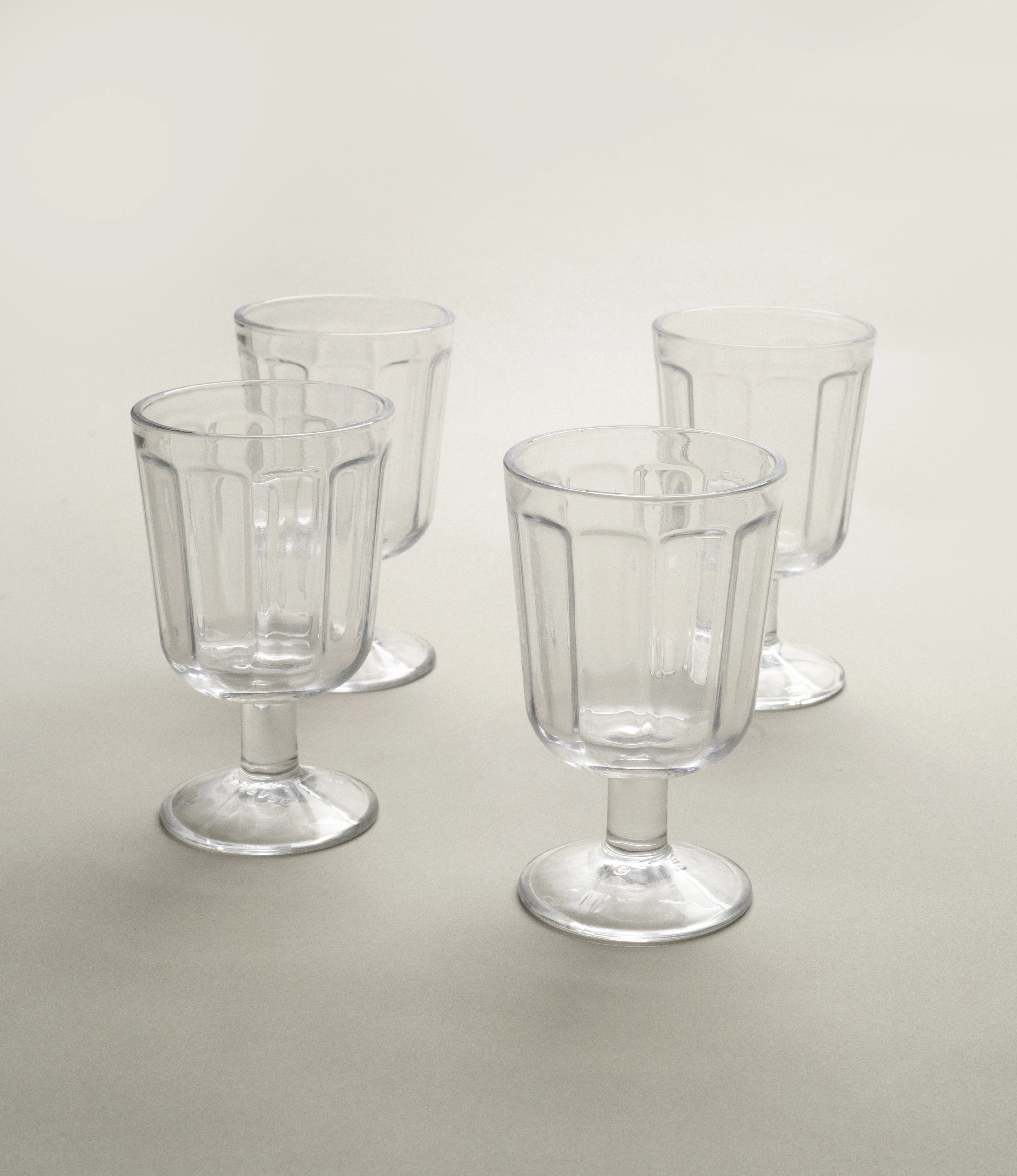 A set of four clear glass white wine goblets by Serax, featuring a subtle fluted design and short stems, displayed on a neutral light background.
