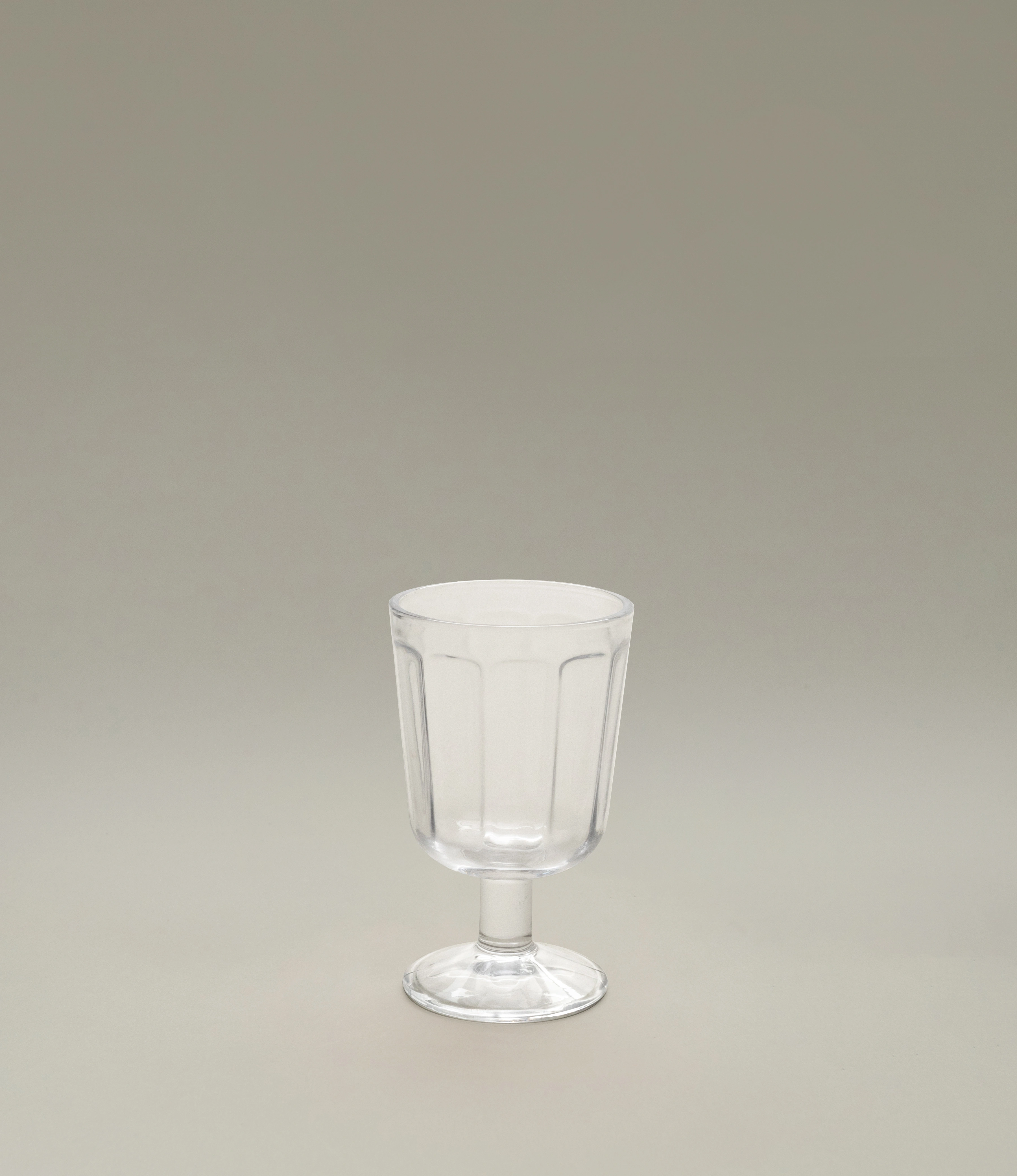 A clear glass white wine goblet by Serax, featuring a subtle fluted design and a short stem, displayed on a neutral light background.