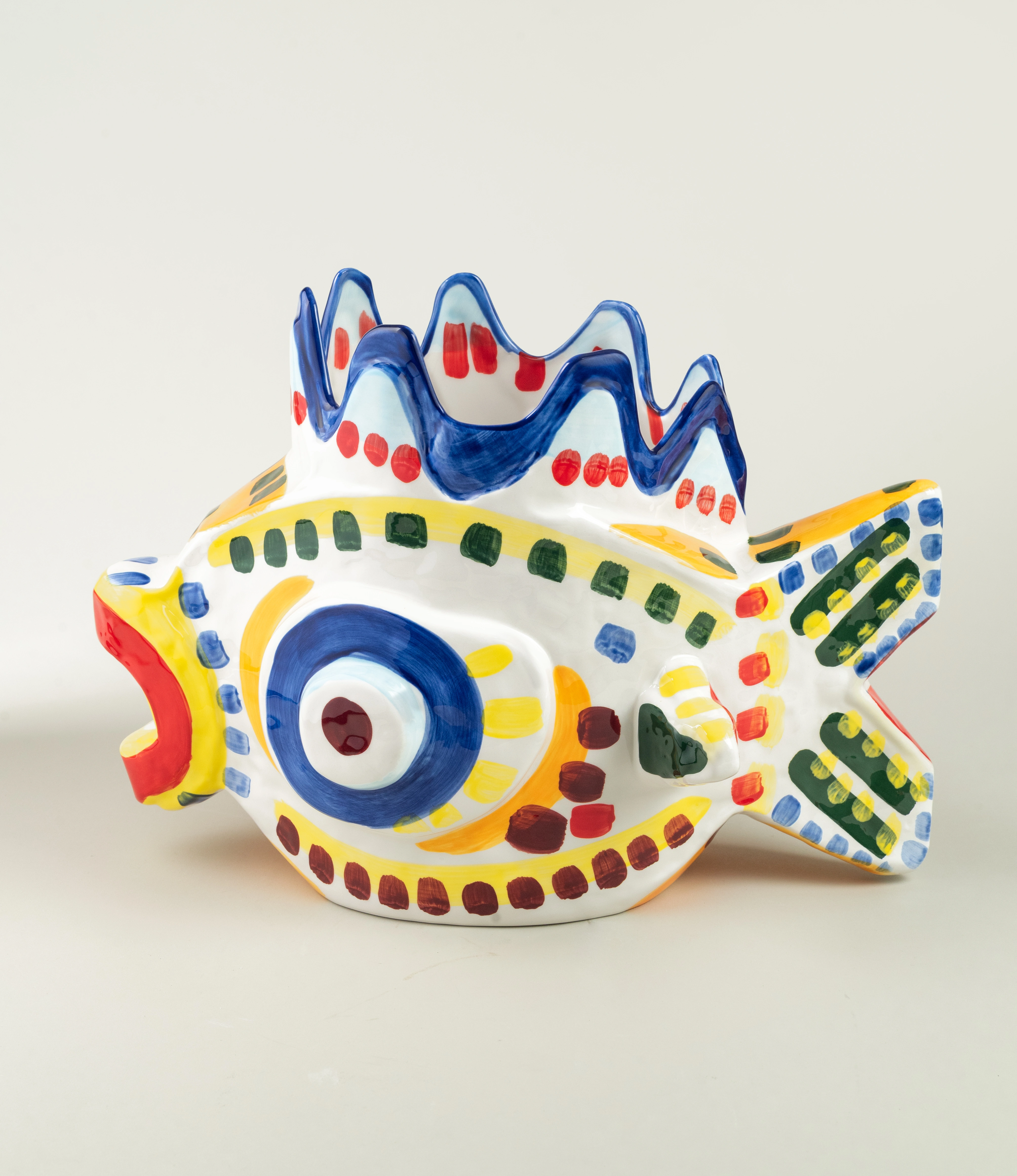 Sicily Fish is a handmade ceramic vase. The item is handpainted in a colorful green, blue, yellow and red pattern. The bold product is designed by Bisignano.