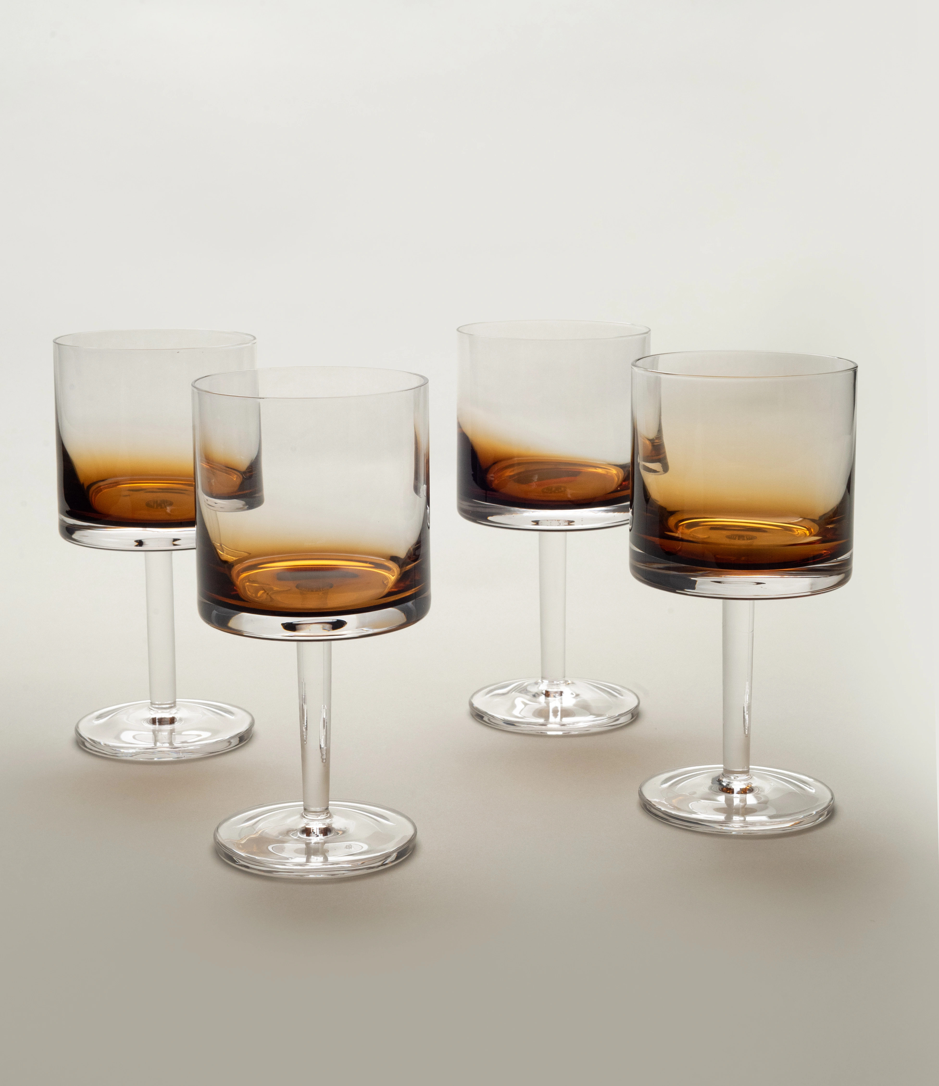 A set of four Serax Zuma red wine glasses, featuring a stylish amber gradient at the base of the bowls, arranged elegantly on a light neutral background.