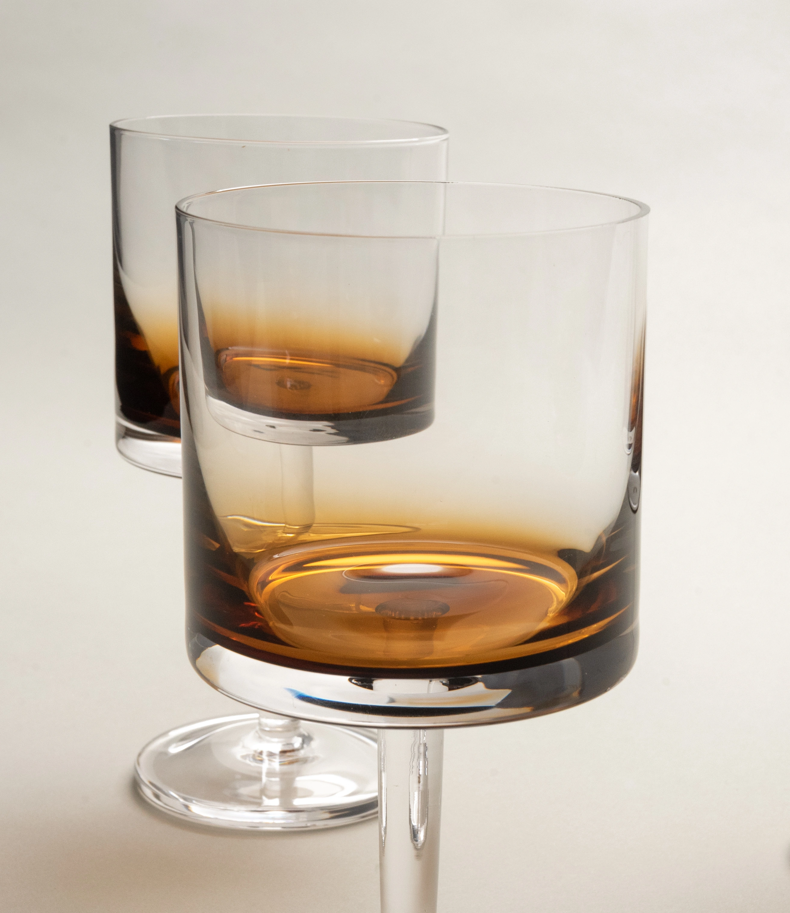 Close-up view of two Serax Zuma red wine glasses showcasing their elegant amber gradient design and slender stems on a neutral background.