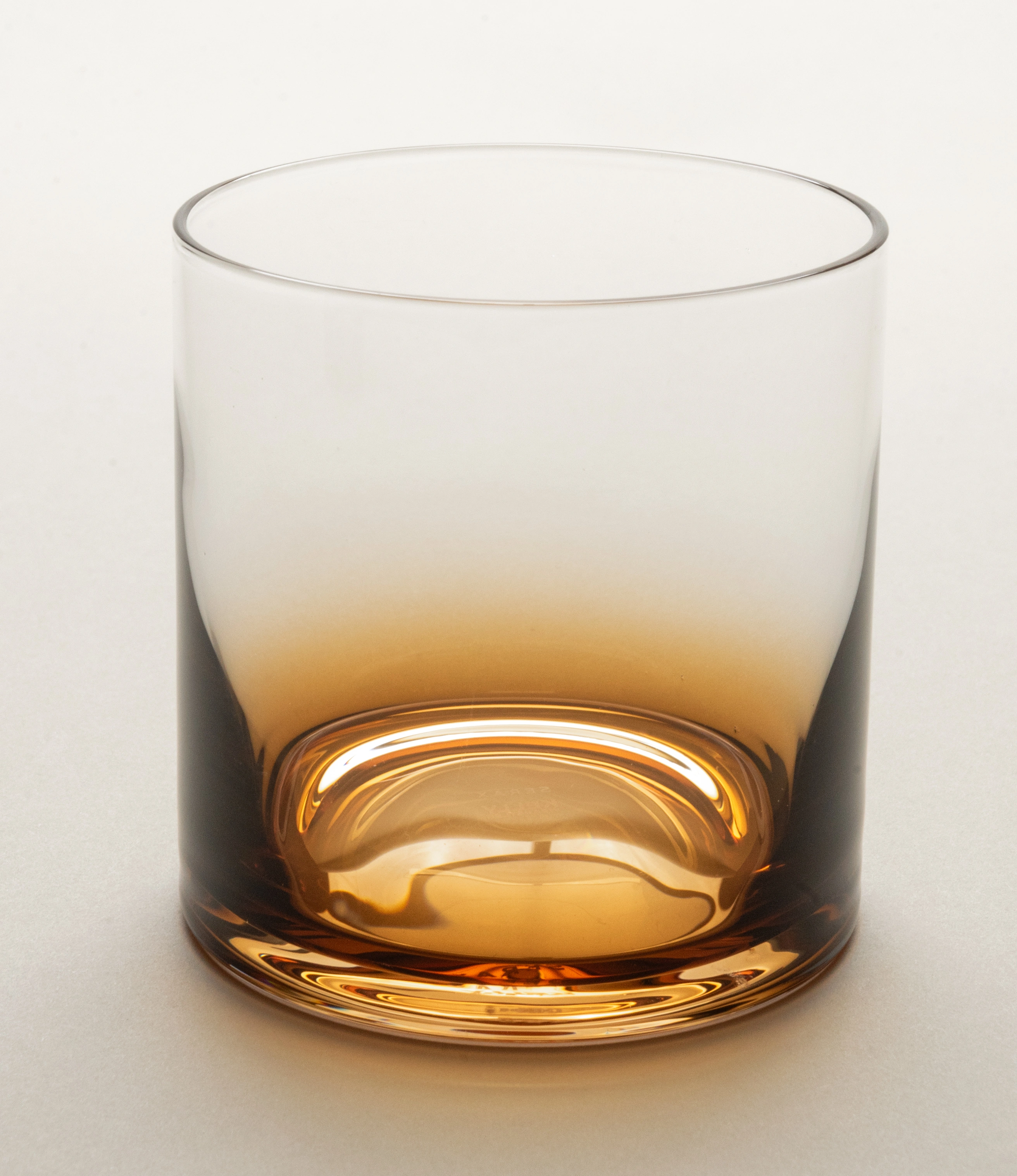 Close-up of Serax Zuma whiskey glass showcasing its amber gradient and intricate craftsmanship, highlighting the base details and modern curvature.