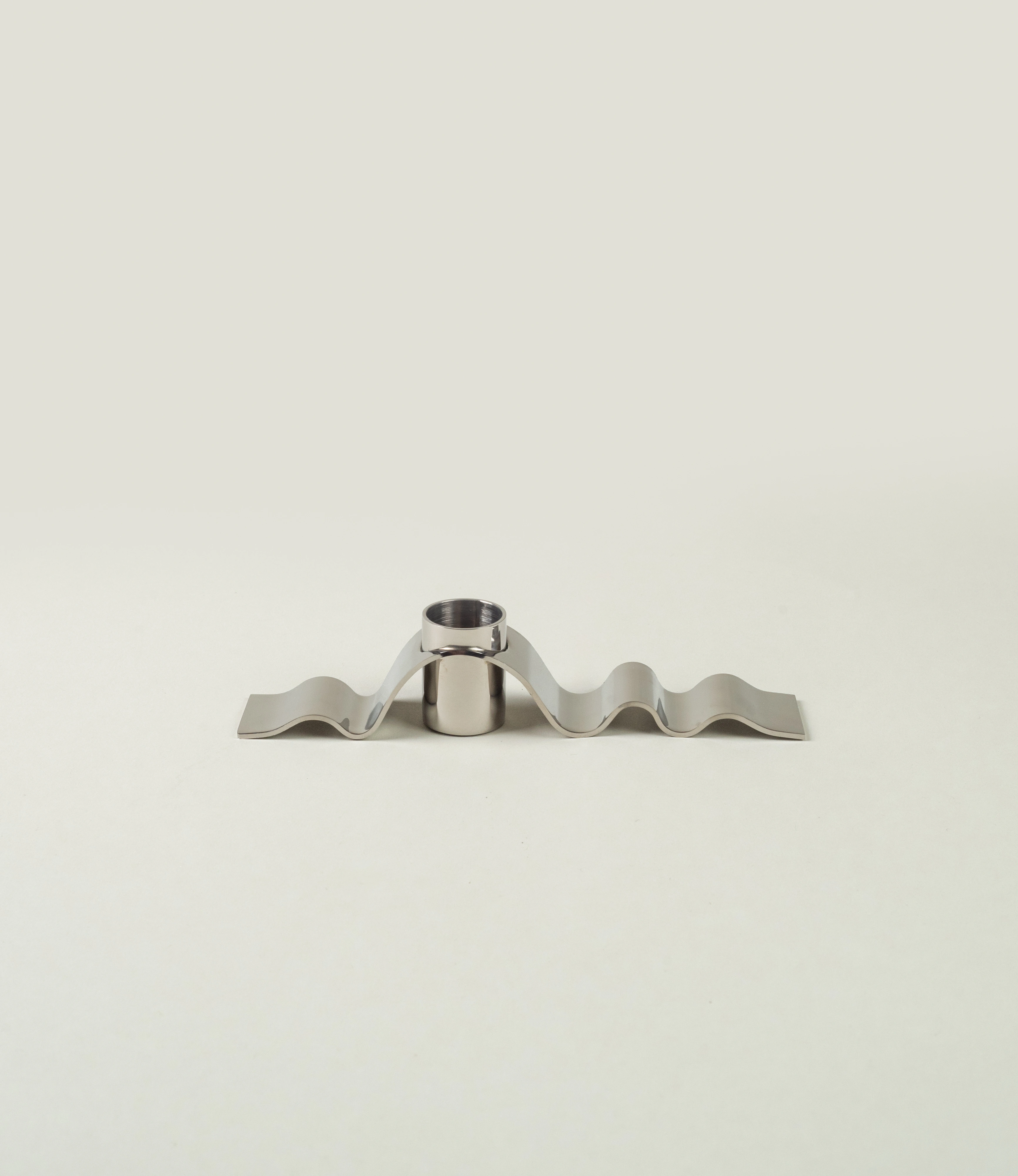 Wave candle holder from Stences. The item is made of a polished stainless steel. The hole for the candle is surrounded by the subtle wavy chrome material. Looks just as a ribbon.