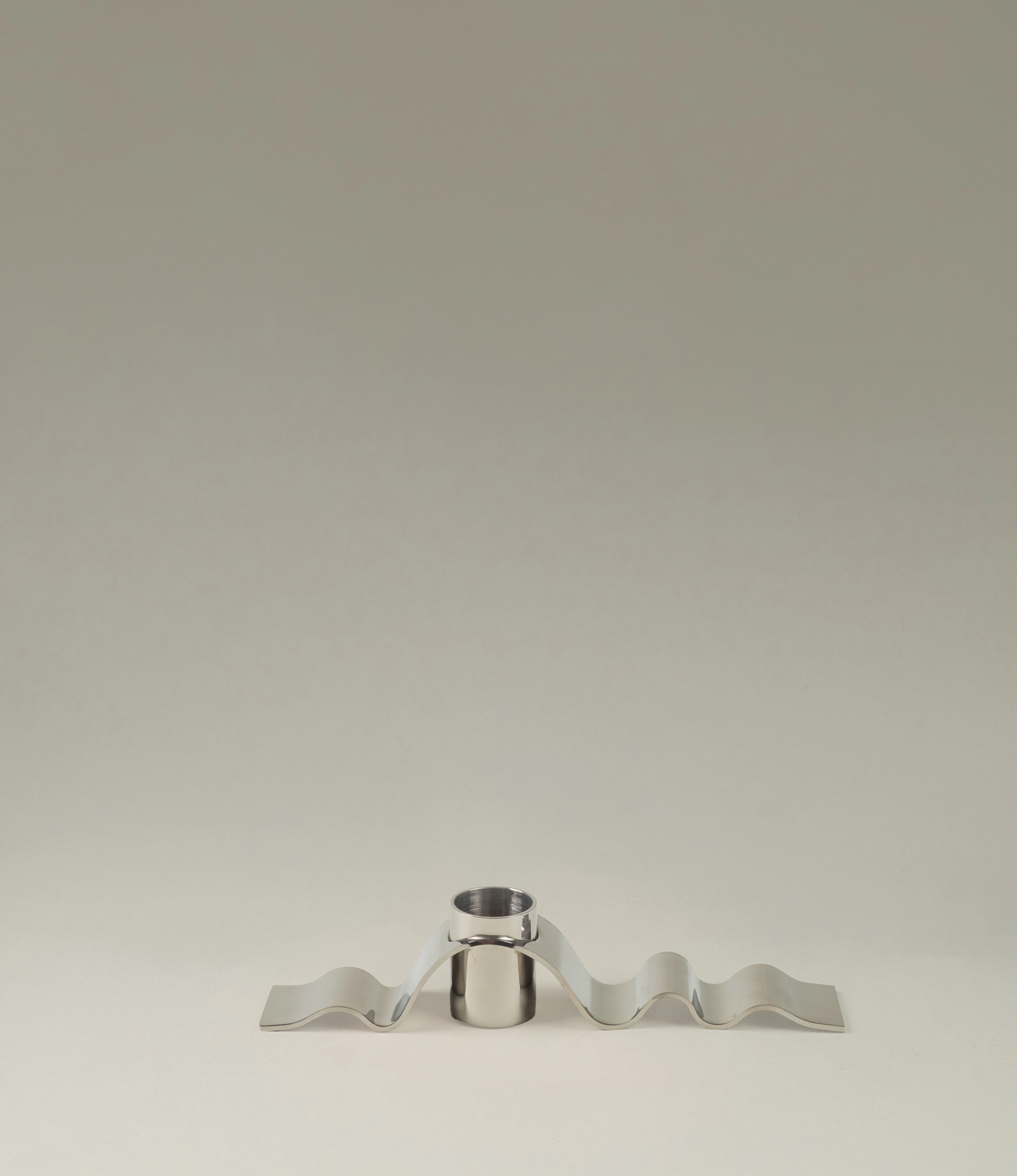 Wave candle holder from Stences. The item is made of a polished stainless steel. The hole for the candle is surrounded by the subtle wavy chrome material. Looks just as a ribbon.
