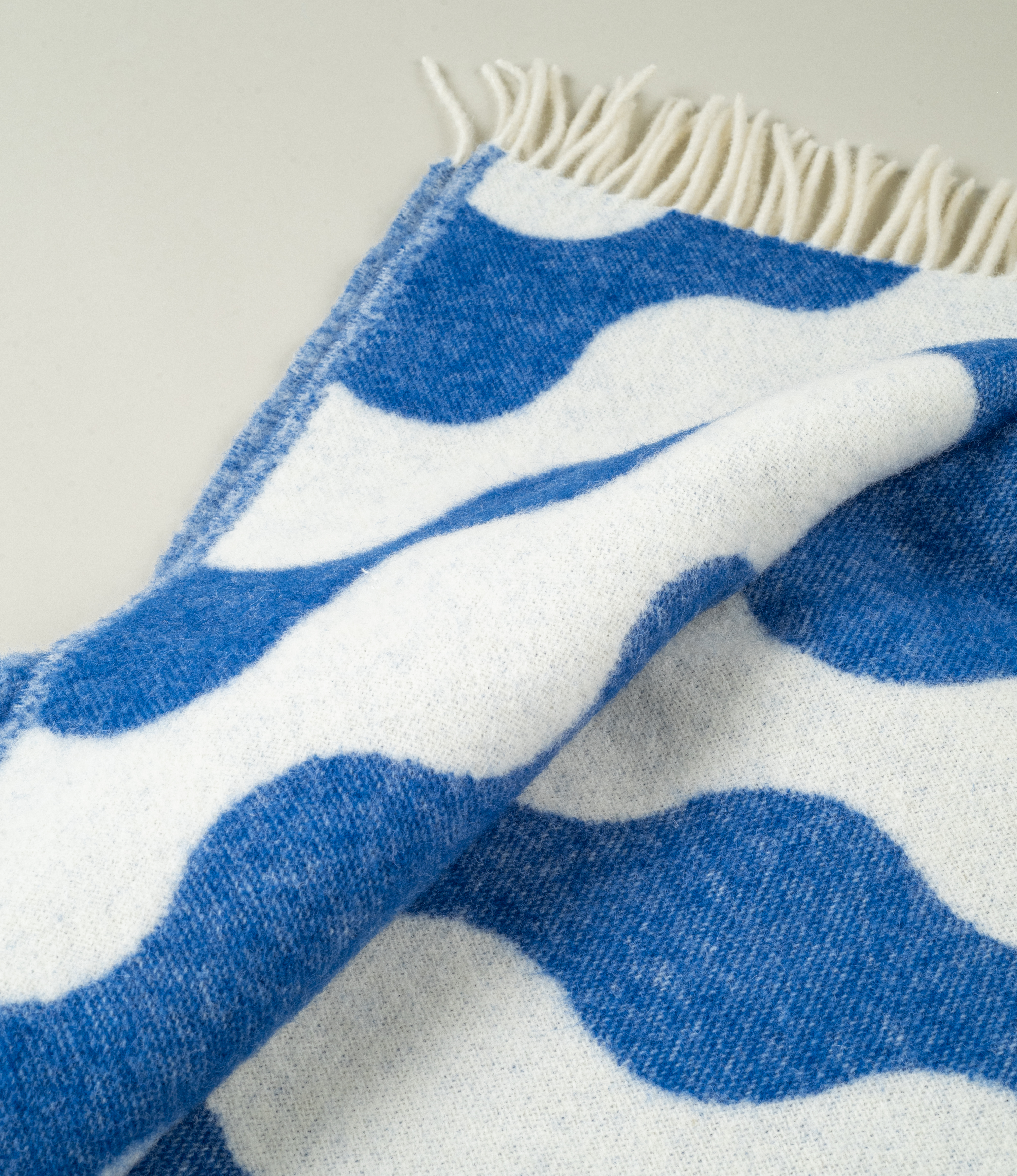 Close-up of Medusa Blanket texture – A detailed view of the jacquard-woven pattern in blue and off-white, showing the soft texture of 100% New Zealand wool.