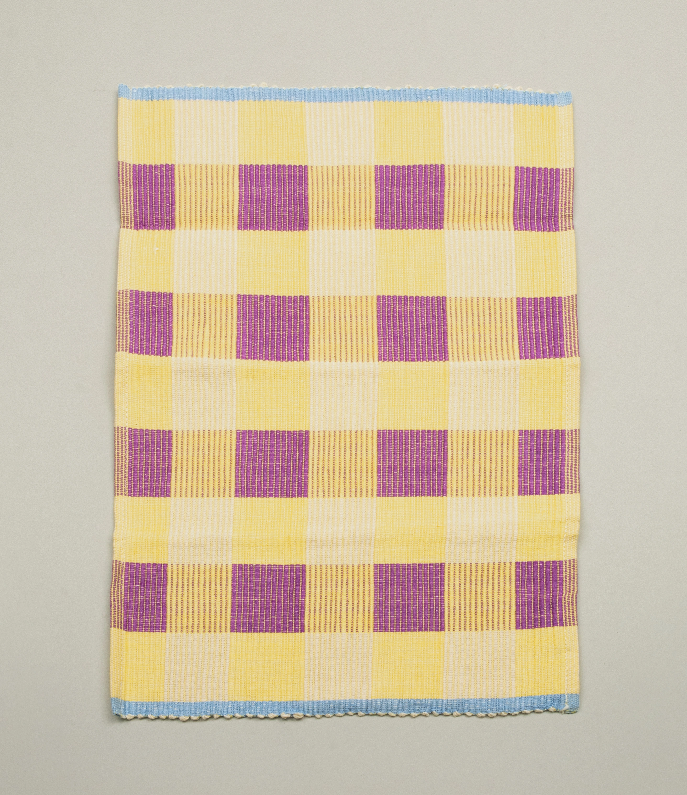 Lilac and Yellow variant of Tarta Gelatina's Merienda PlaceMats. The product has a light blue edge on the shorter sides. The item is shot from top on this product picture.