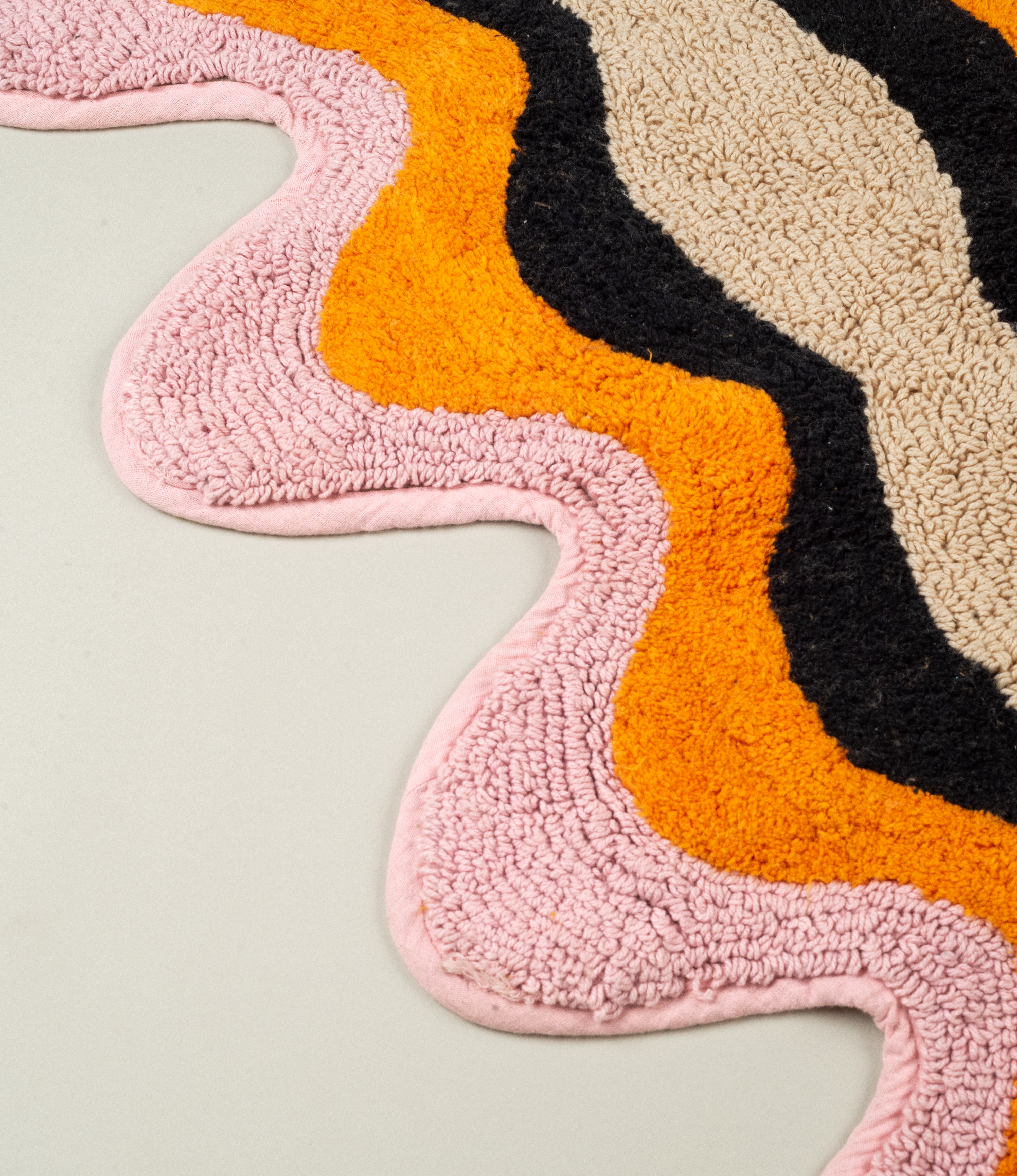 Close-up of Tarta Gelatina Plankton Bathmat’s rich color palette and tufted cotton texture, emphasizing the organic wave-like design.