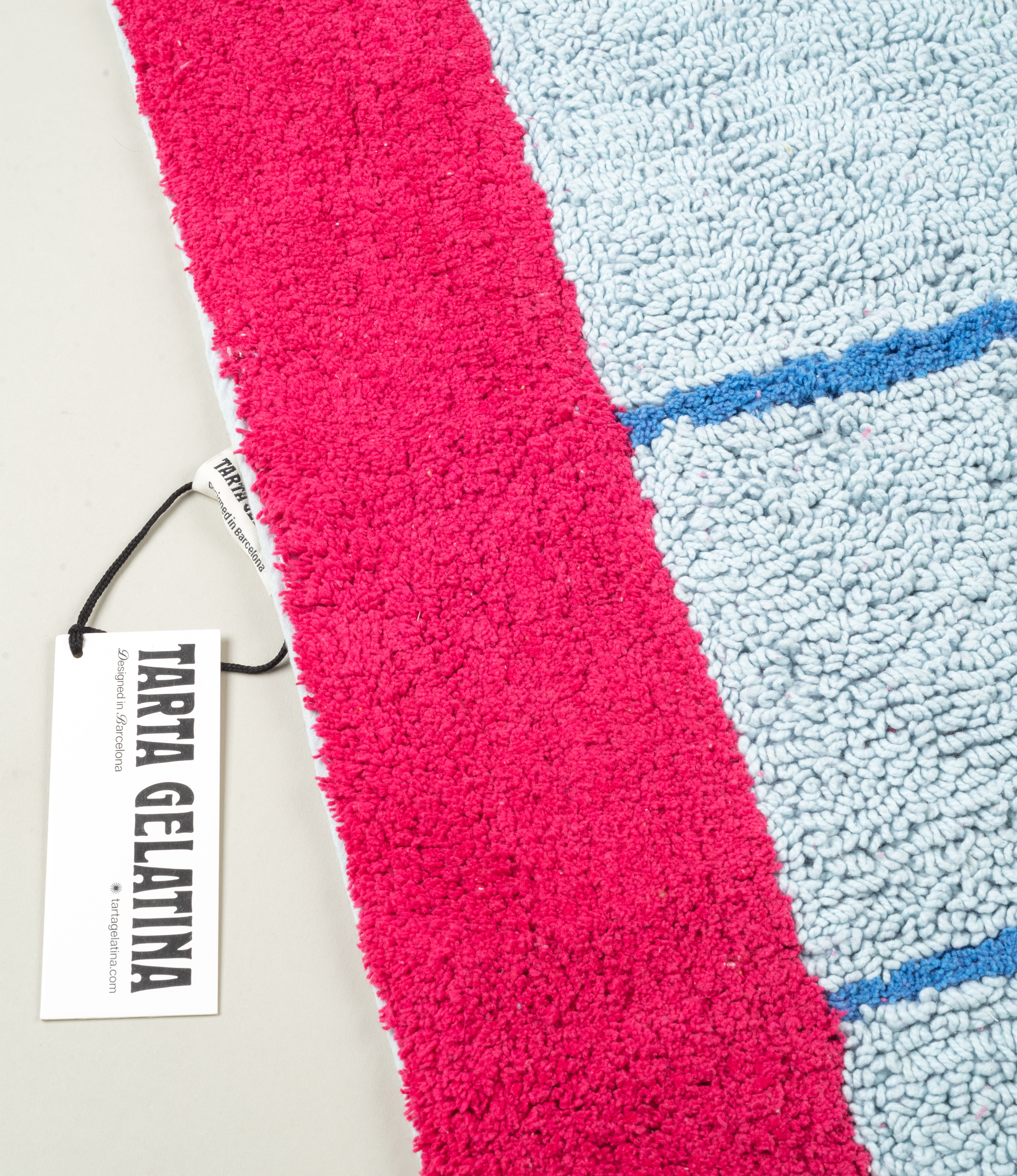 Detailed close-up of Tarta Gelatina Poolside bathmat's pink and blue hues, showing the plush texture of the cotton material.