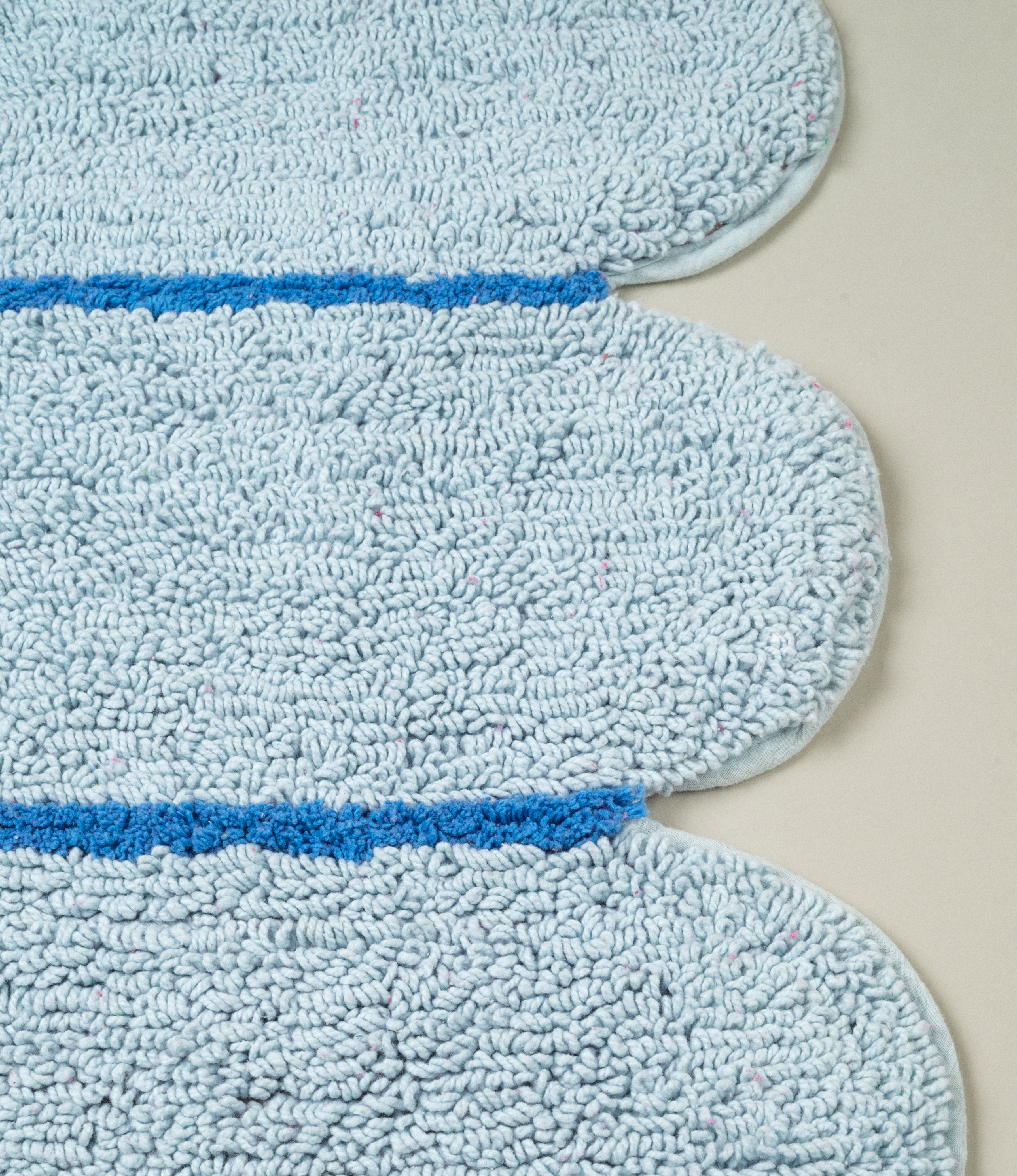 Close-up of Tarta Gelatina Poolside Bathmat scalloped edge, emphasizing the high-quality tufted construction and blue color pallete.