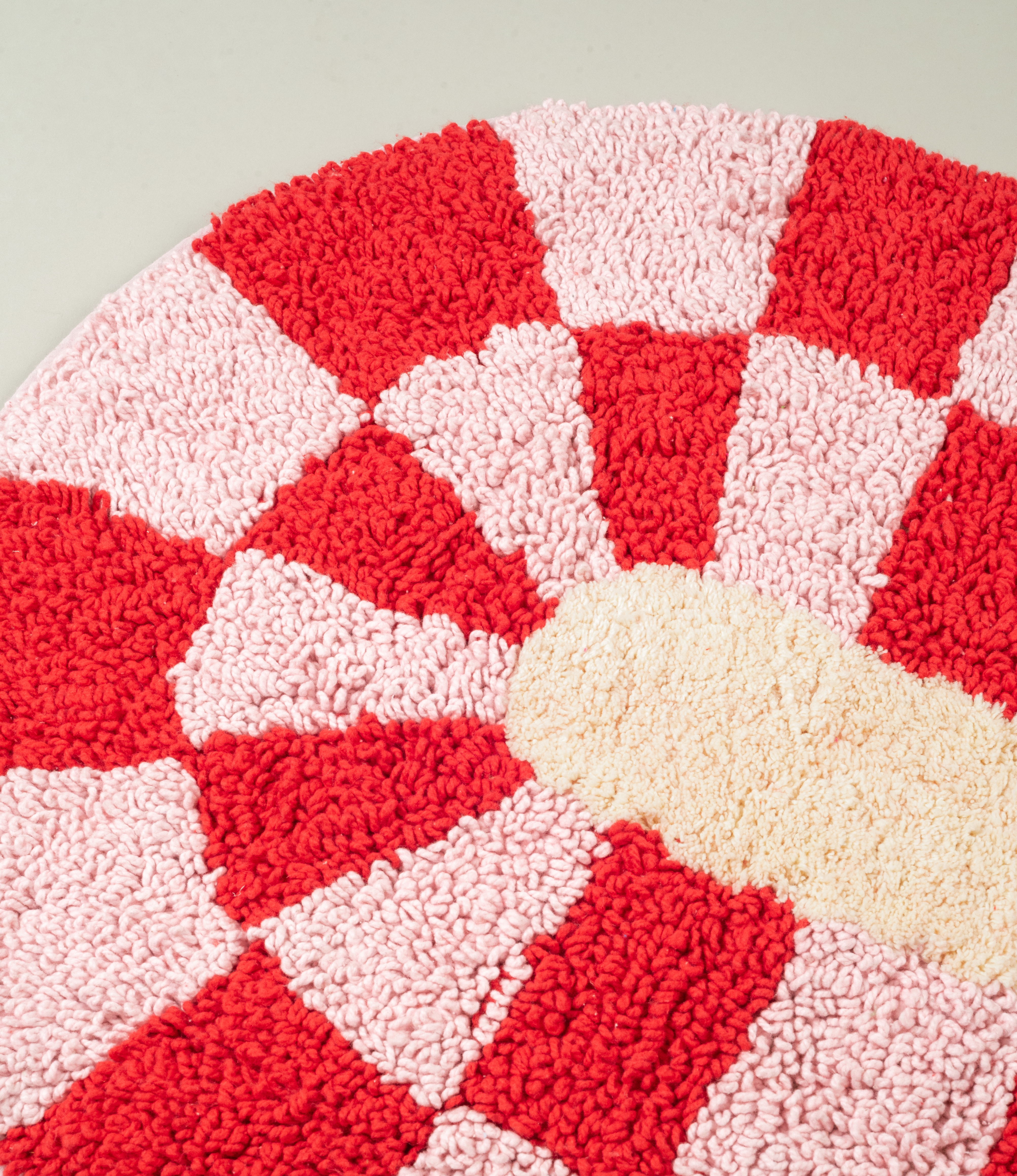 A close-up shot of the Miranda Bathmat’s soft loops and vibrant red and pink checkered design, emphasizing its tactile comfort.
