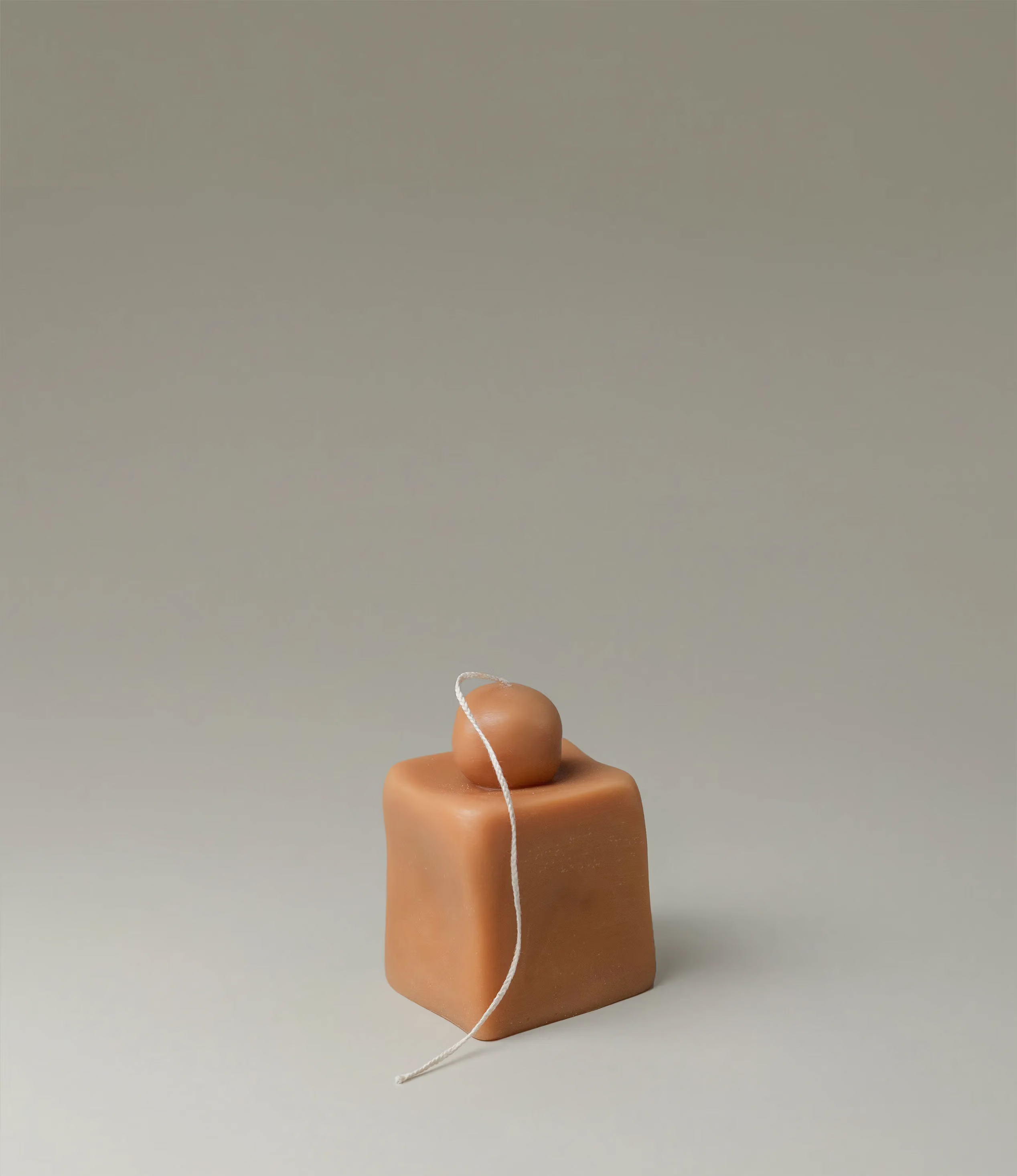 Fonz from Ann Vincent is a sculptural candle. The silhouette of the product looks like a rectangle with a smaller rounded shape on top. The candle wick is quite long and has a braided texture.