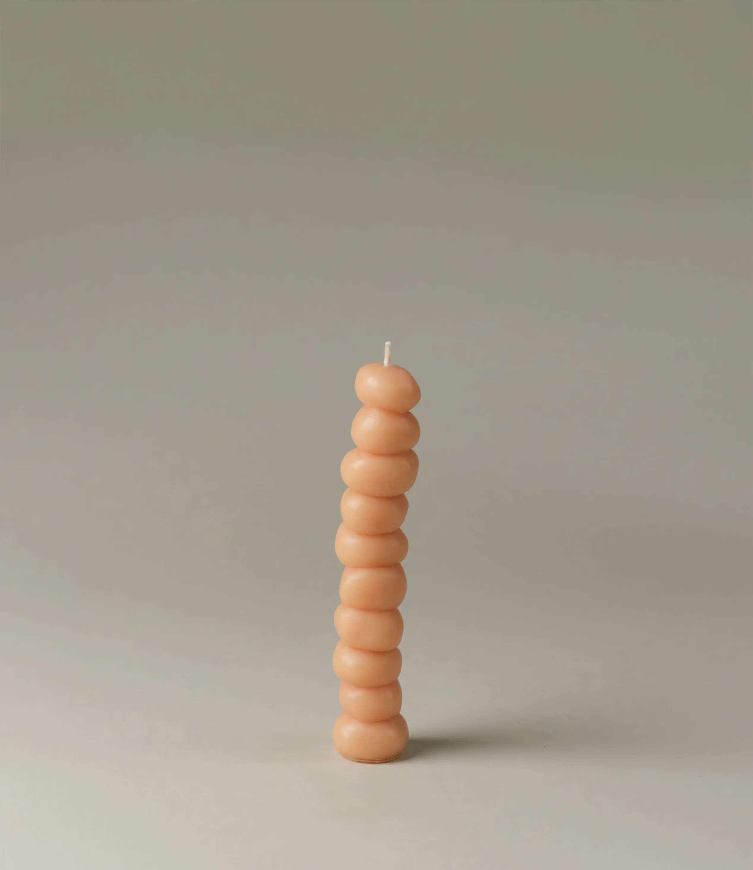 Grape Candle from Ann Vincent has the shape of grapes stacked on top of each other. It has a light nude color.