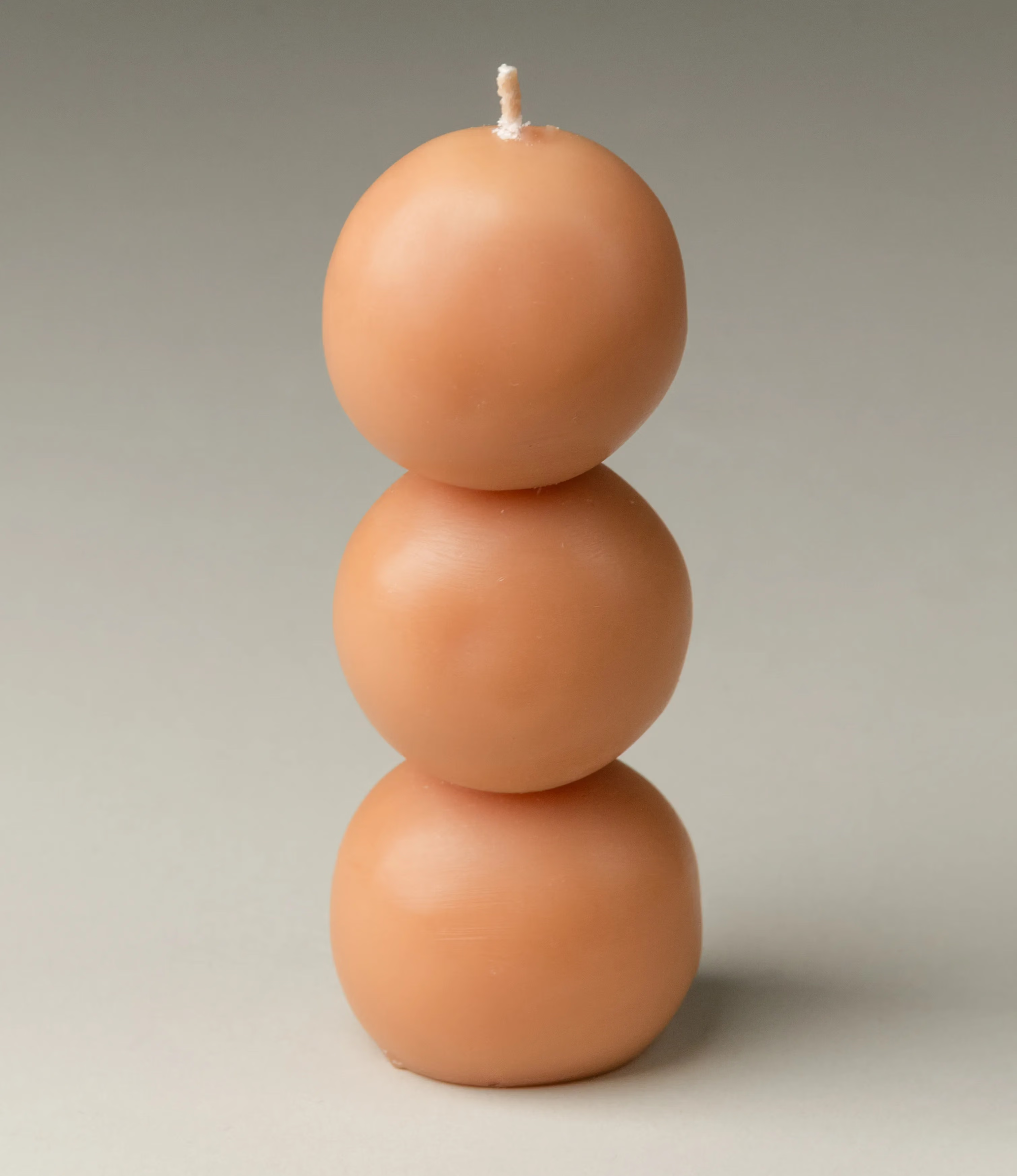 One of the three candles. It has a beige color and it has the shape of three balls stacked on top of each other