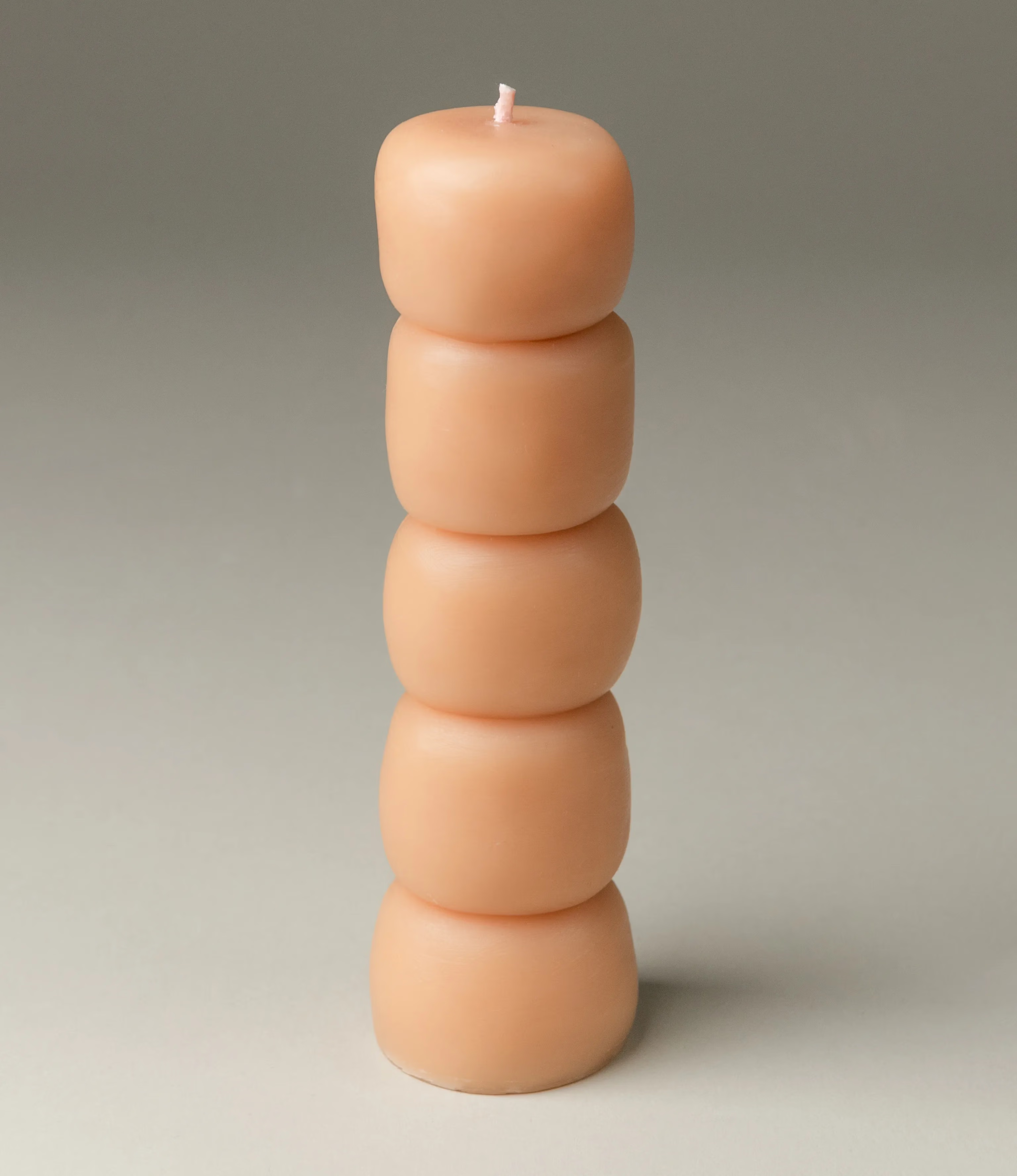 One of the three candles of the Piu Set from Ann Vincent. This candle has a nude color and the shape looks like stacked sculpture of soft marshmallows.