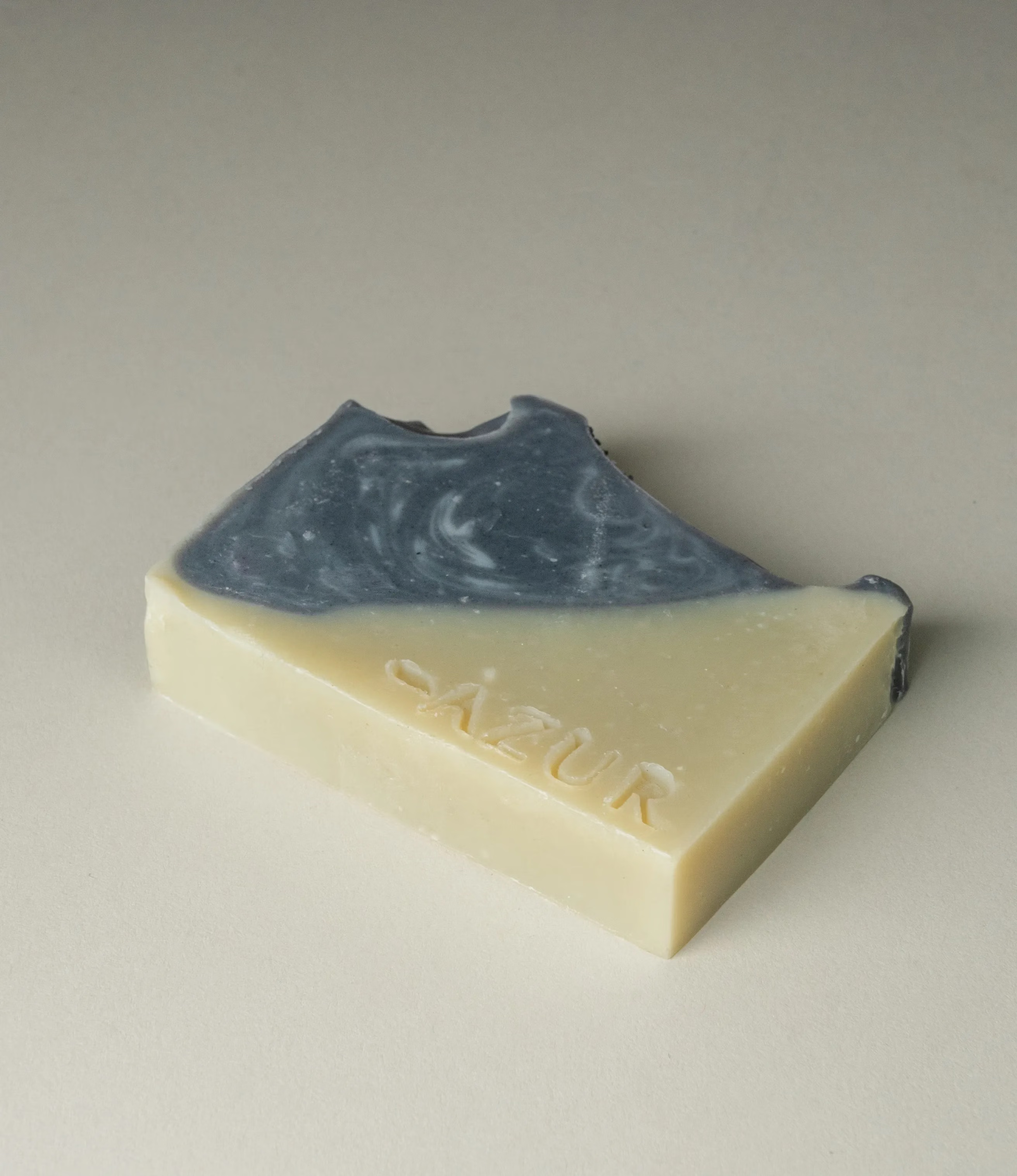 This soap has the scent of Wild Woods and it was crafted by Azur Natural Bodycare. The product merges two colors, light olive and dark grey. The top of the soap looks like the waves of the ocean. 