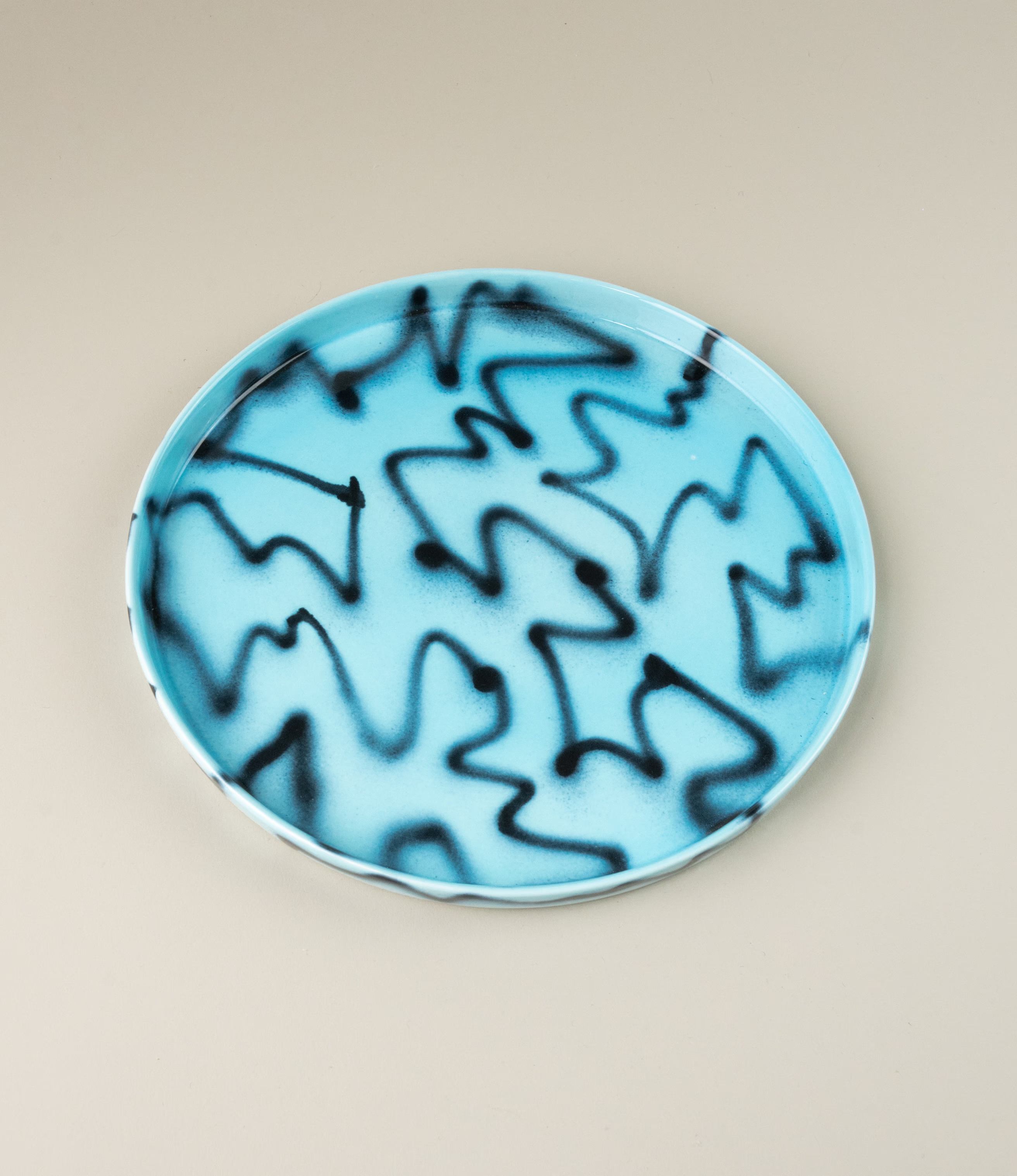 Blue Pizza Tray from Frizbee Ceramics. The tray is coming in the soothing light blue color matched with the contrasting black zig-zag pattern.